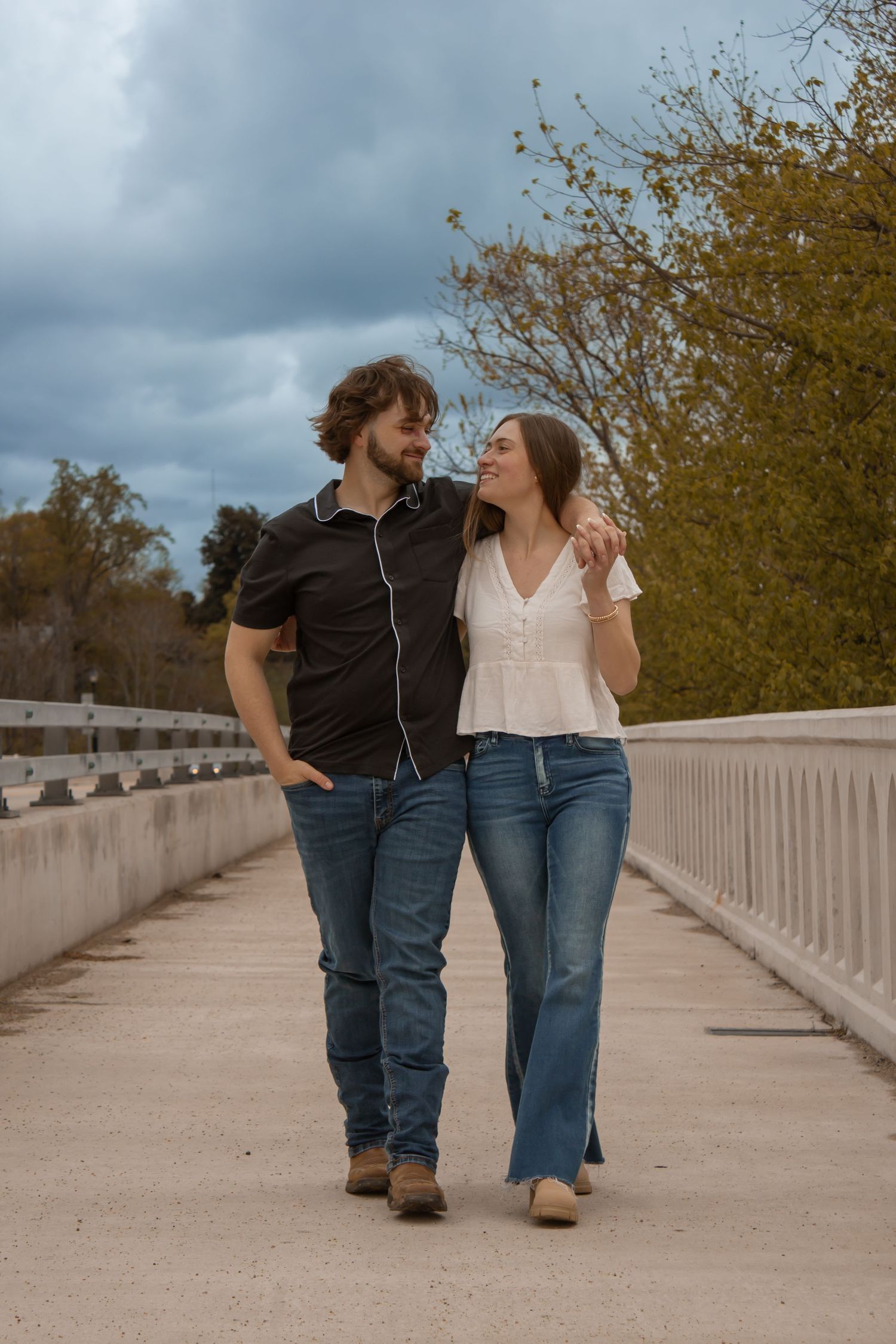 picture of couple, engagement session, they're both in the middle of the bridge looking at each other.