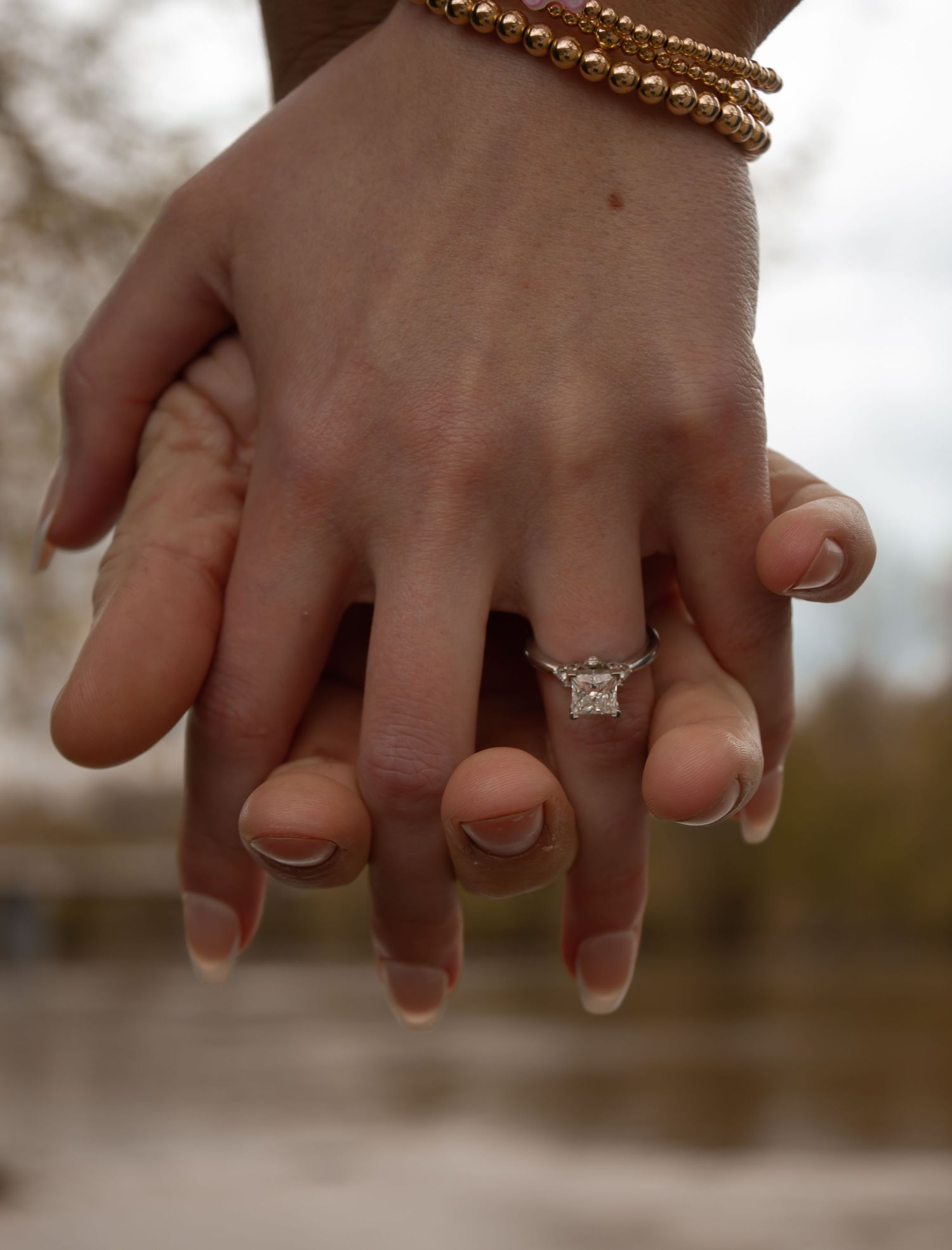 picture of couples hands. the engagement ring is visible