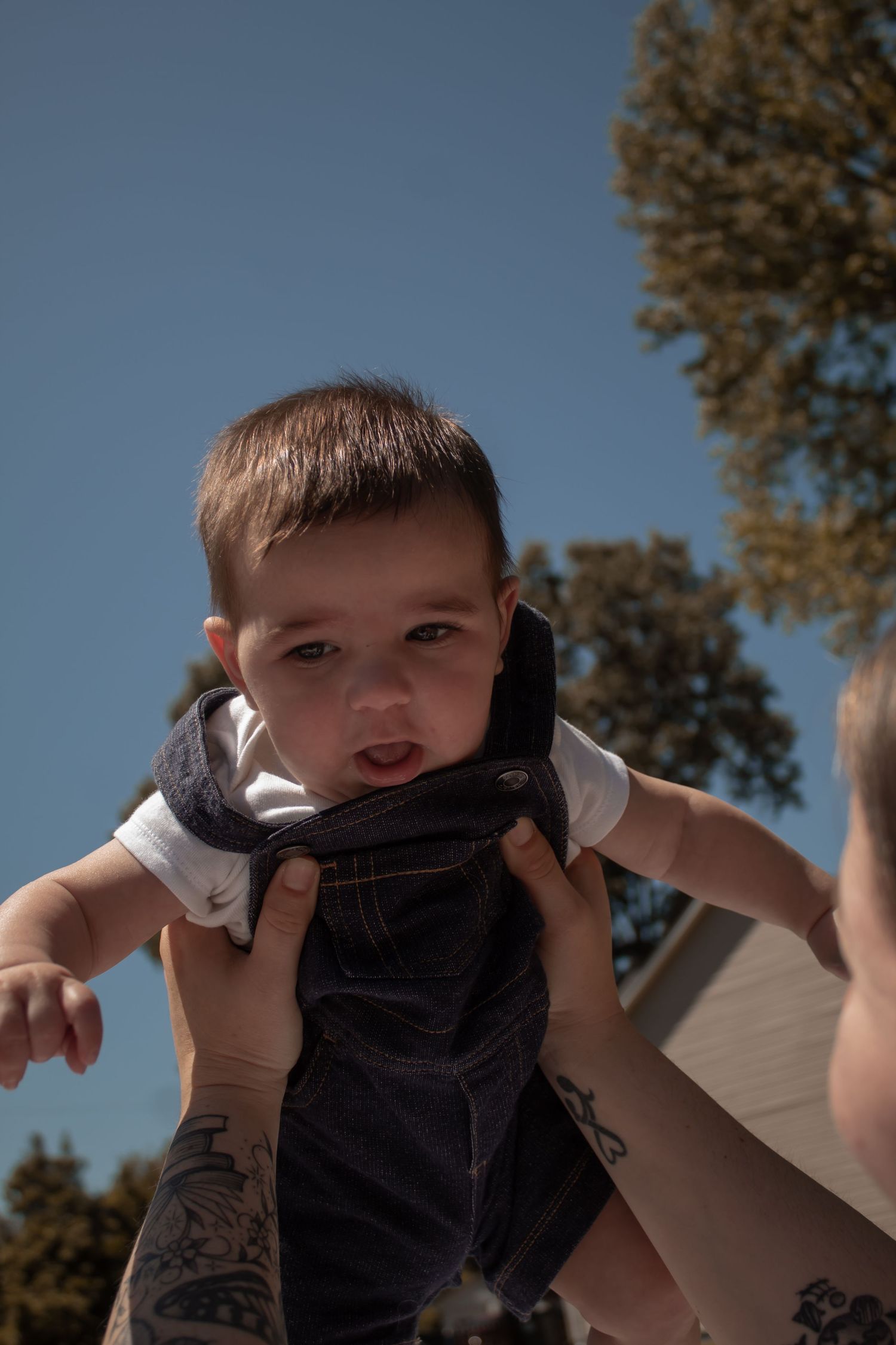 picture of baby boy being lifted up by mama. golden hour