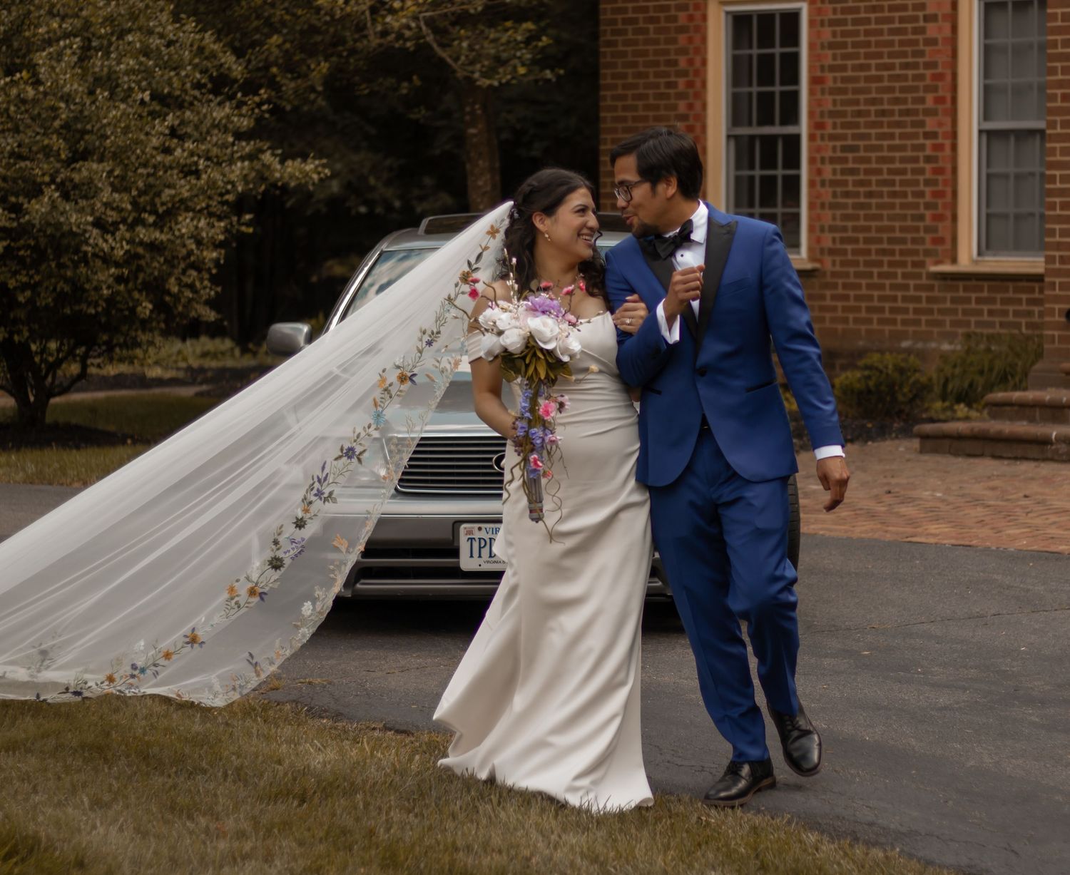 picture of bride and groom outside church building standing in front of their car.
