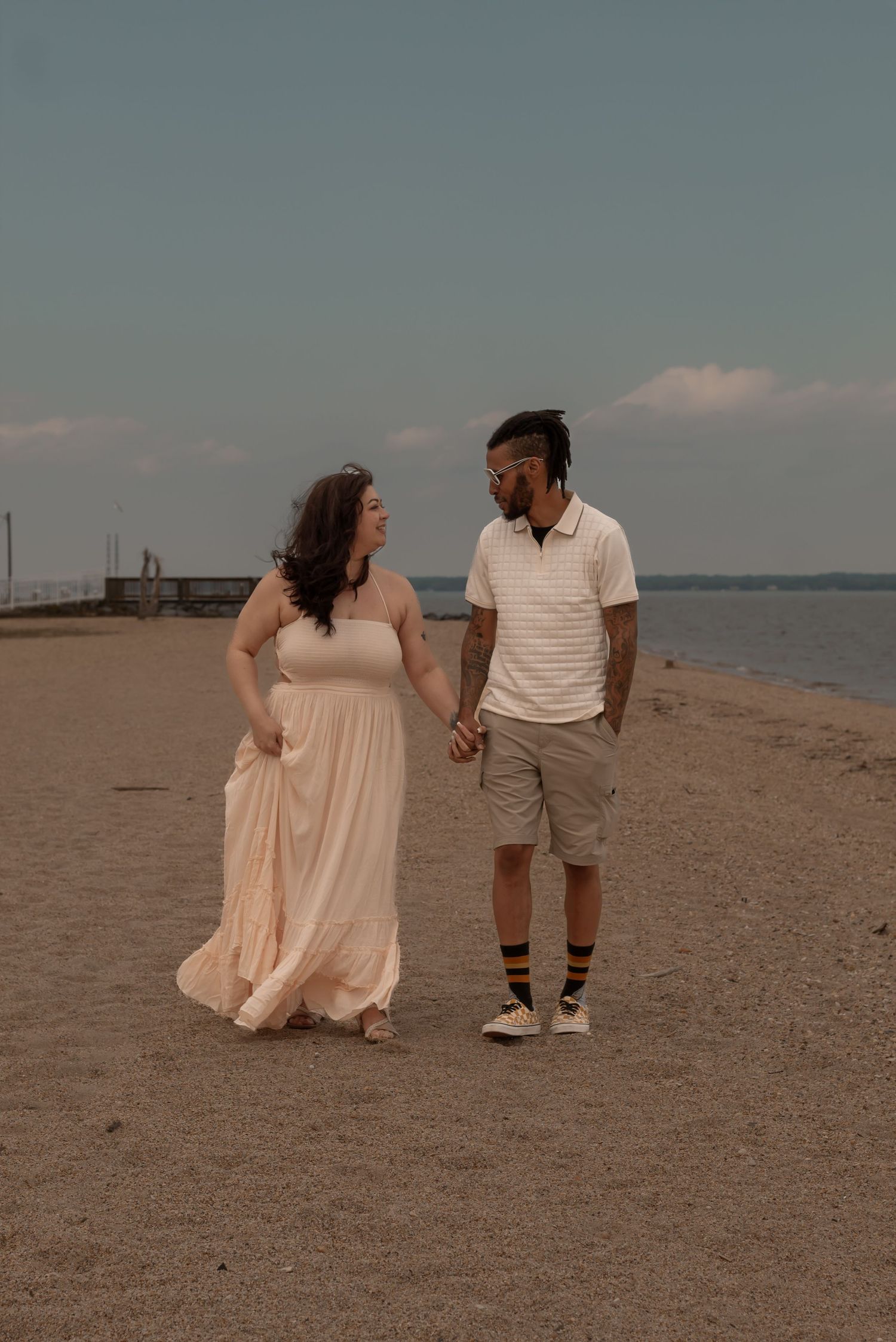 picture of couple at beach, looking at each other while walking along the shoreline.
