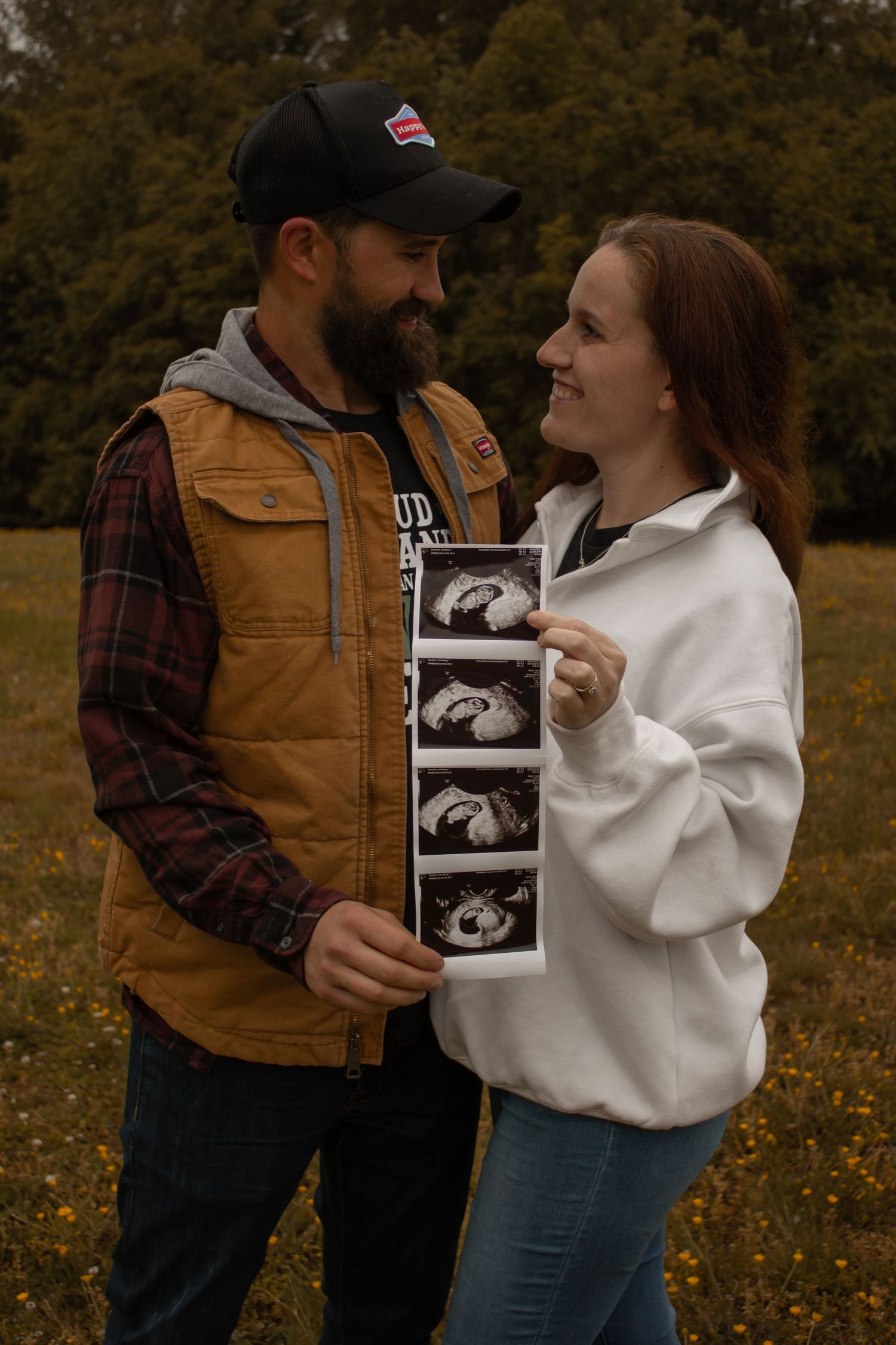 picture of couple holding up sonogram picture of their new bundle of joy. they're looking at each other