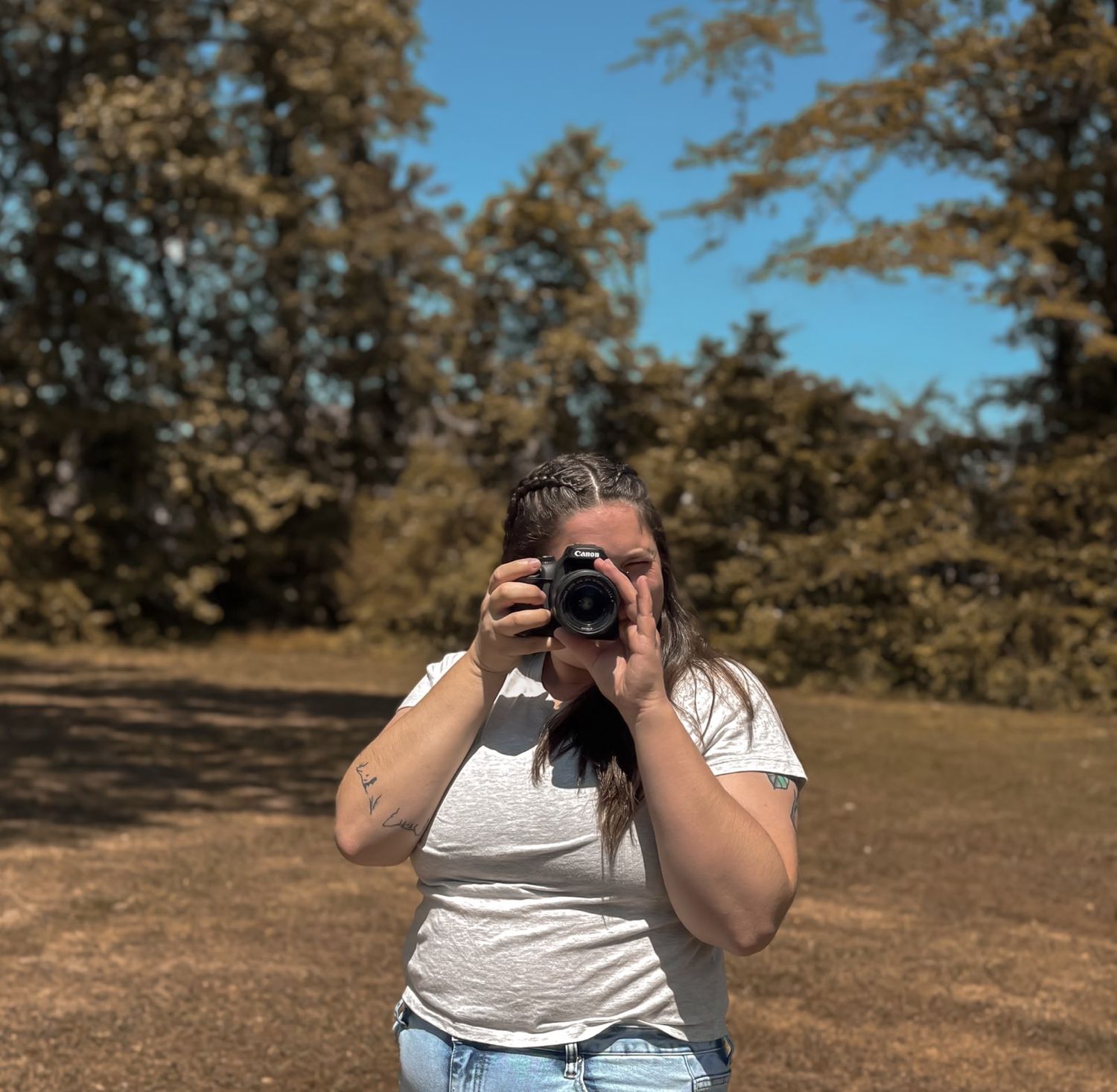 picture of amber dunnigan in forest, holding camera up to her face as if she's about to snap pictures of you, close up picture.
