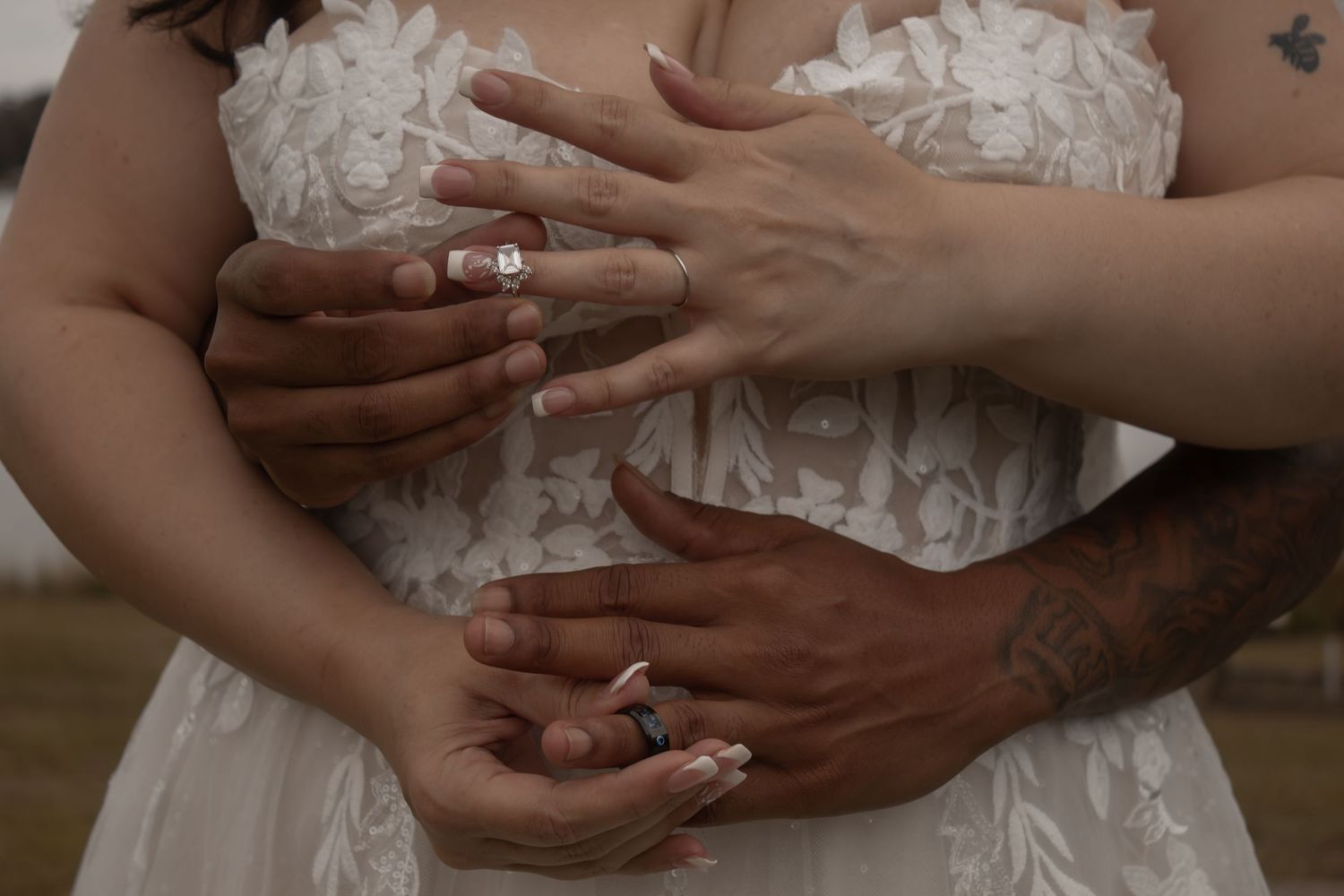 picture of bride and groom's hands about to slip their rings on to their fingers.