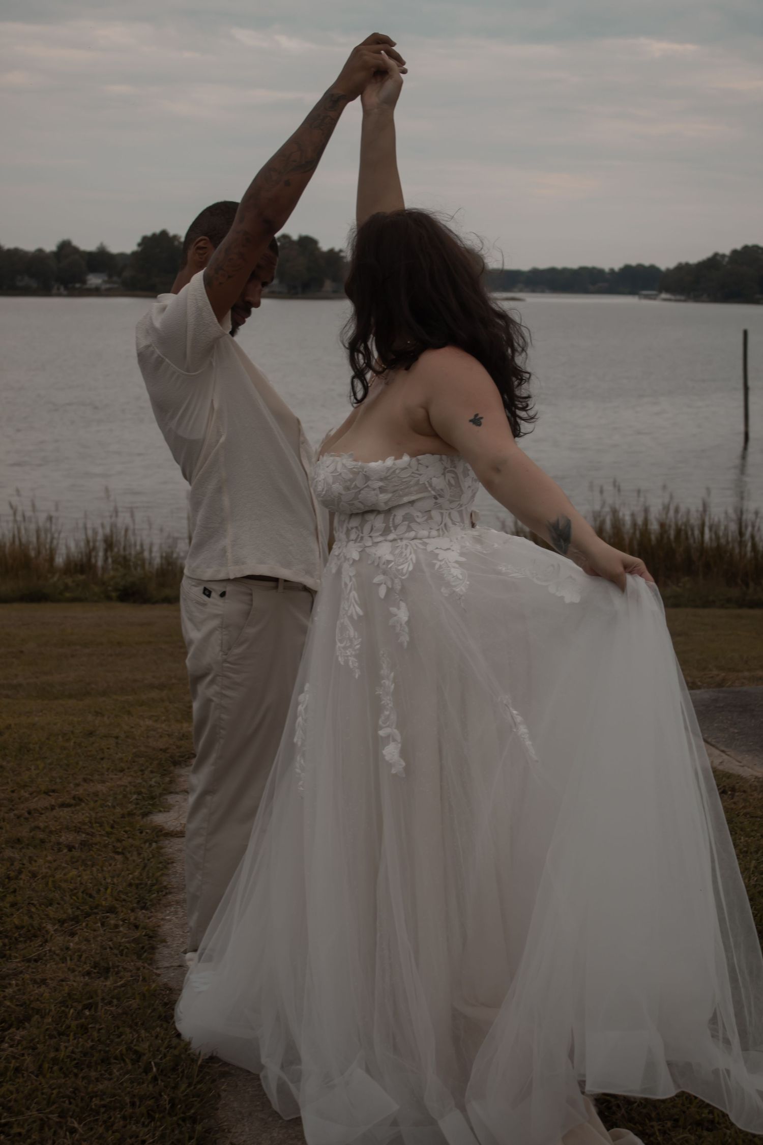 picture of bride and groom near beach, guy twirling girl while she is hold her dress.