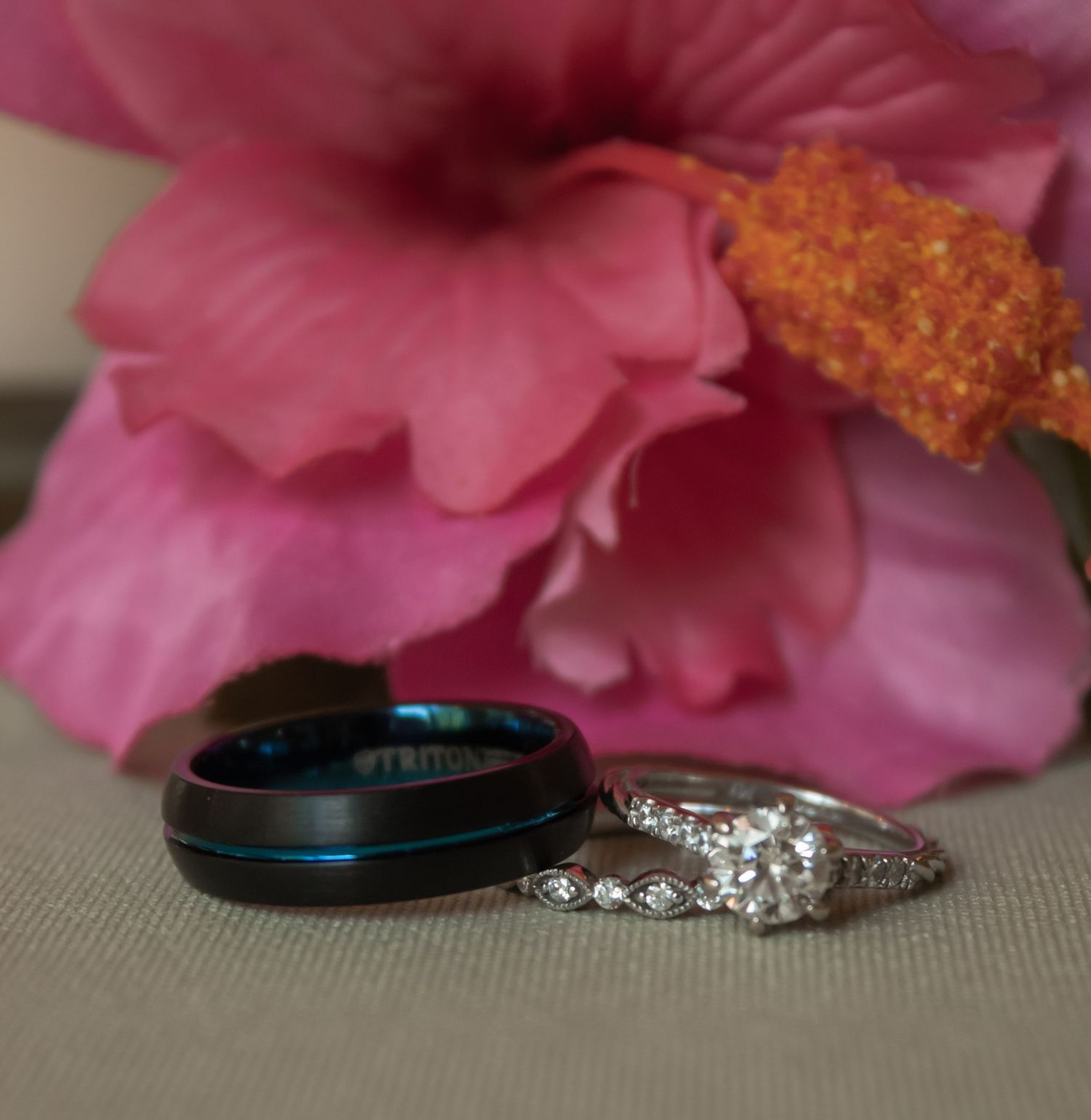picture of bride and groom's rings with pink flower in the back
