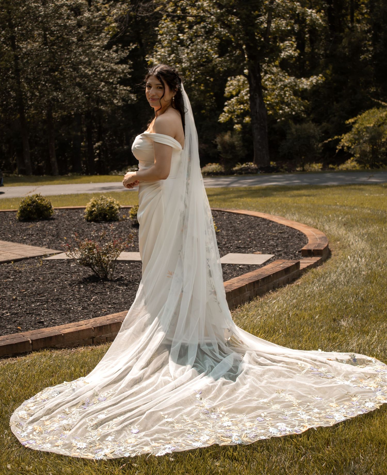 picture of bride by her herself and her veil is nicely spread out behind her as she's looking down.