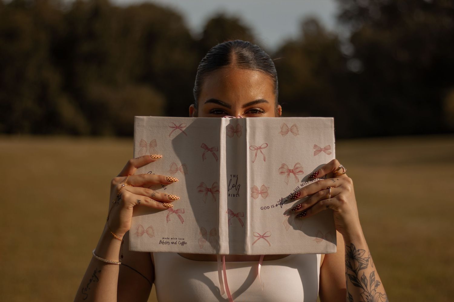 picture of girl holding up a book (bible) halfway up to her face, only showing her eyes
