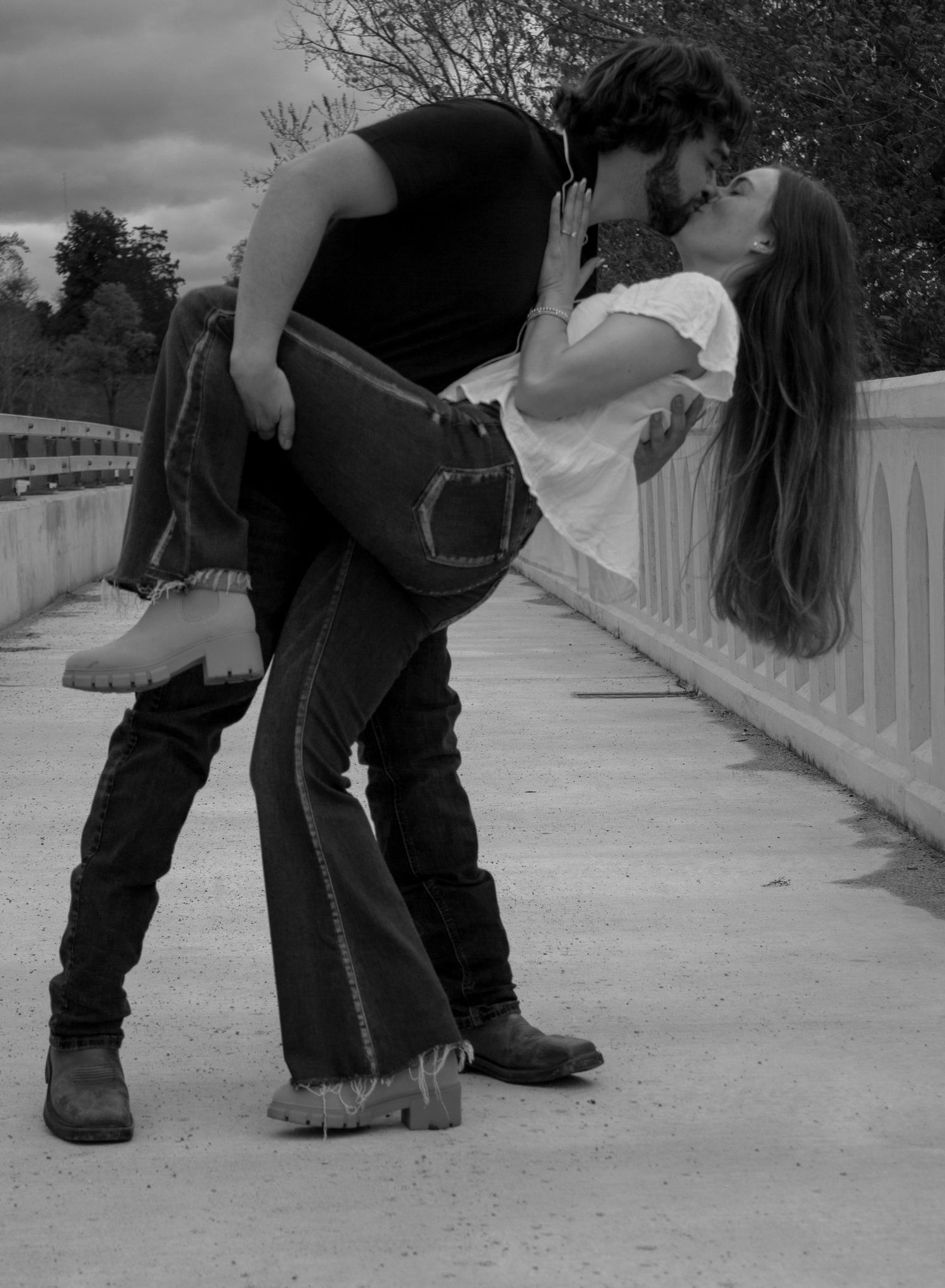 picture of couple on bridge, man is dipping the girl and they are kissing, engagement picture