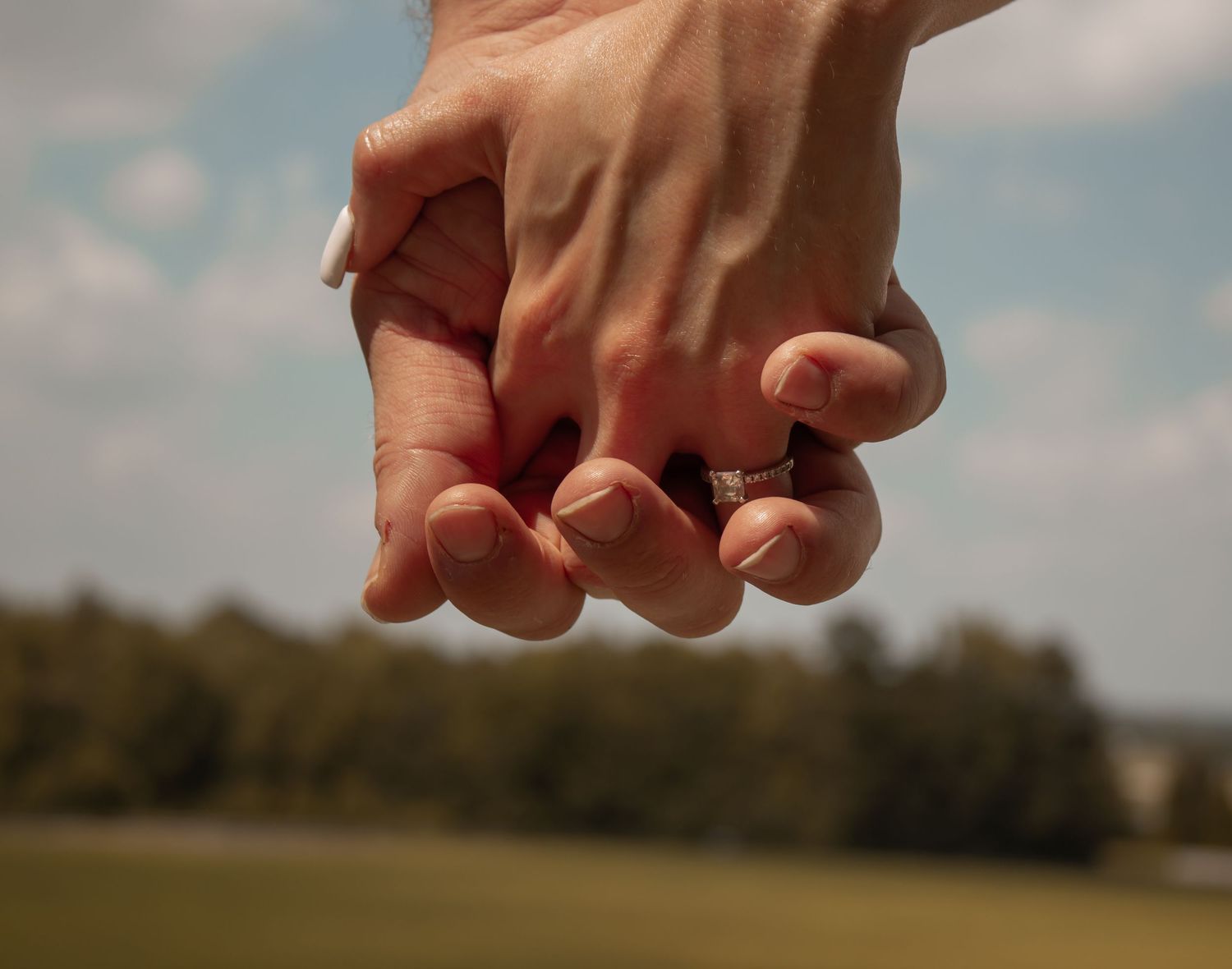 picture of couple's hands in the wild, showcasing the girl's engagement ring