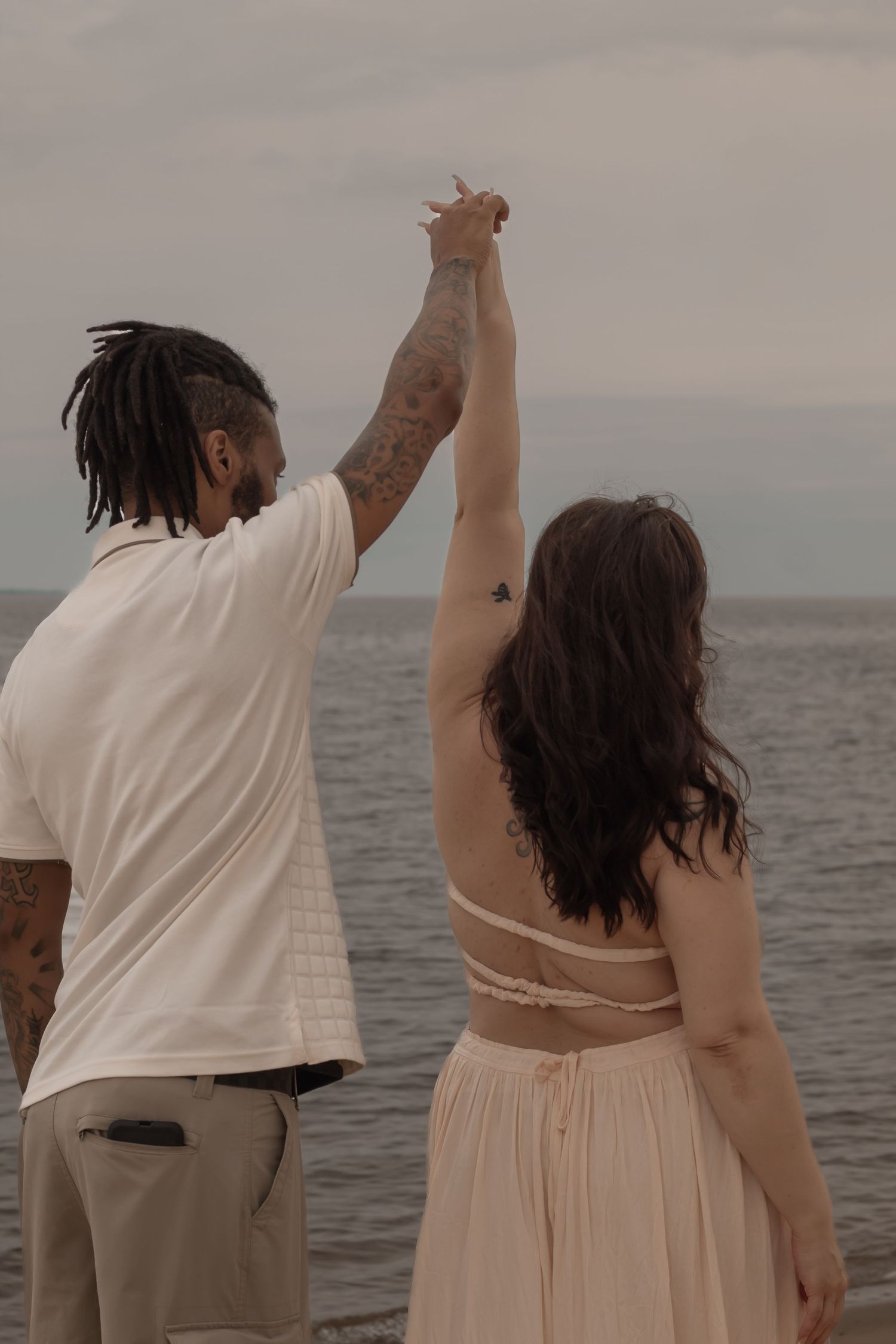picture of couple at beach, guy twirling girl, they're both looking away from camera