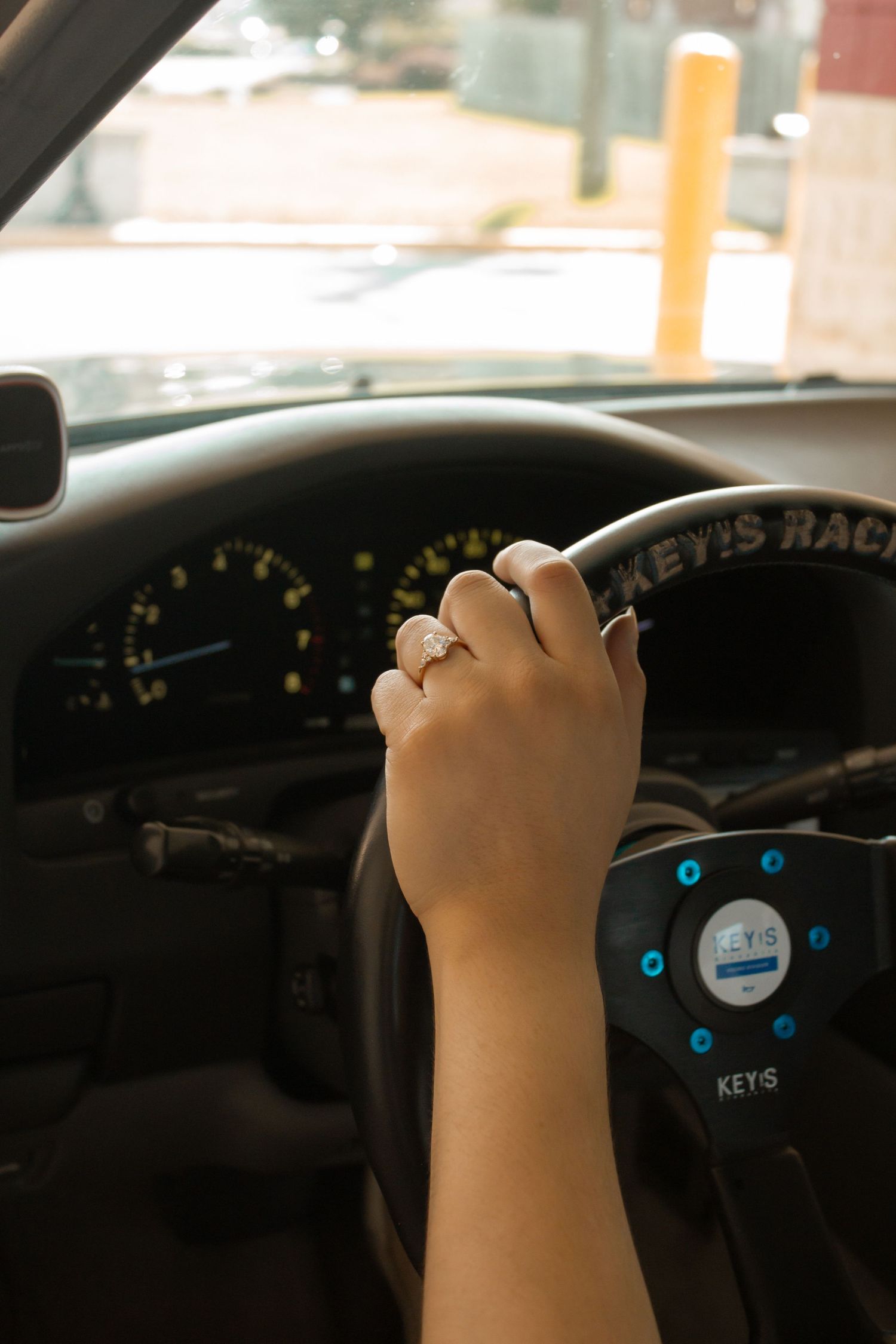 picture of girls left hand holding steering wheel showcasing her ring.
