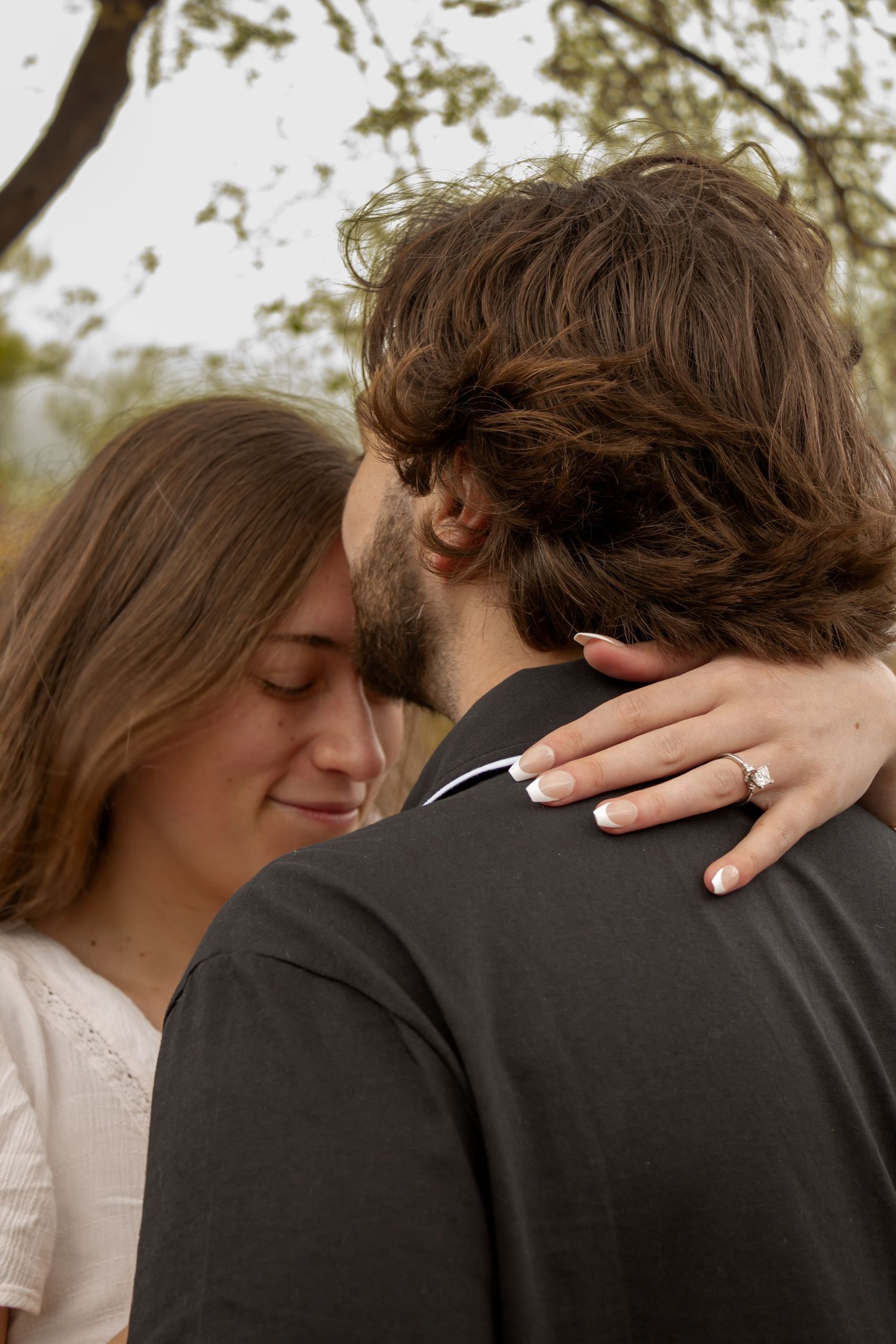 picture of couple, engagement session, man is kissing girls forehead, as she is looking down.