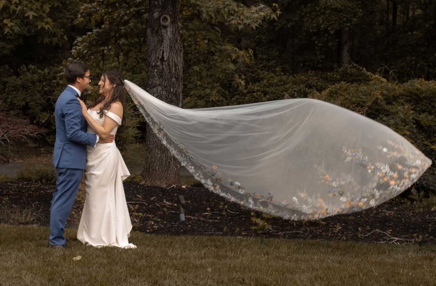 picture of bride and groom holding each other and looking at each other. bride's beautiful veil is flying or floating