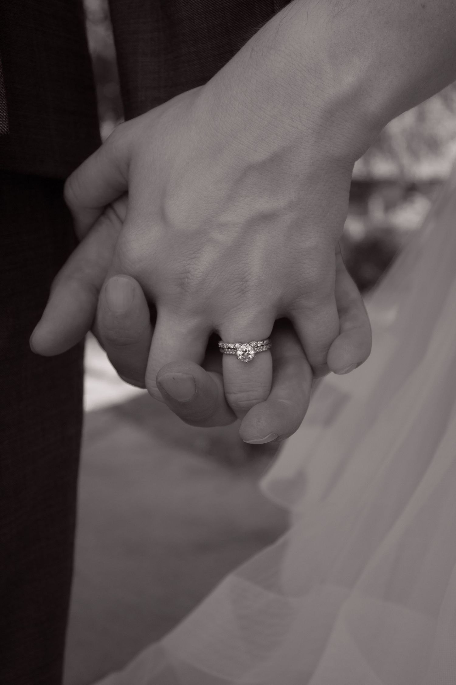 picture of couples hands showcasing the bride's ring in black and white