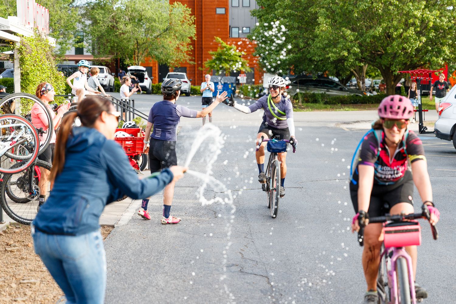 Spectator throwing water on cyclists during a fun urban bike race event.