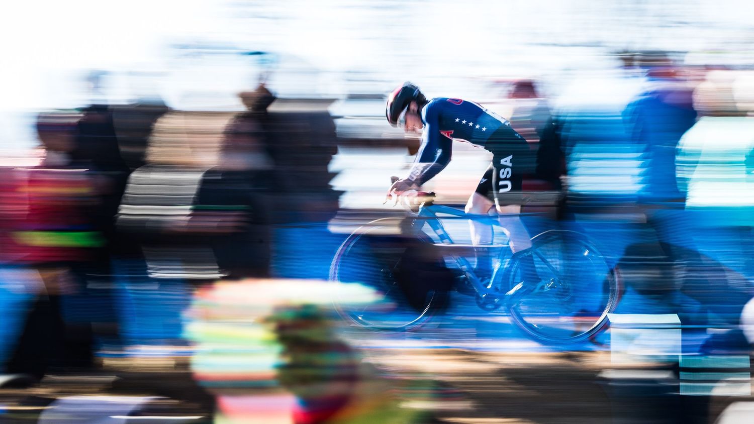 A USA cyclist in motion blur on a track bike, captured with a panning photography technique.