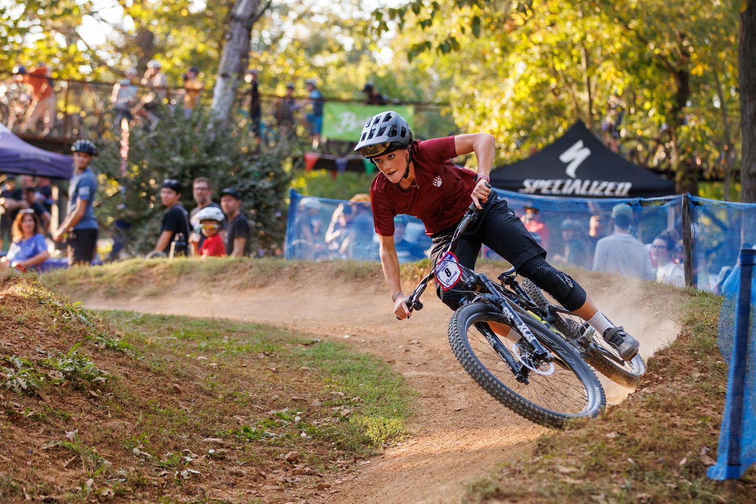 Mountain biker carves dirt berm at Specialized-sponsored MTB race event.