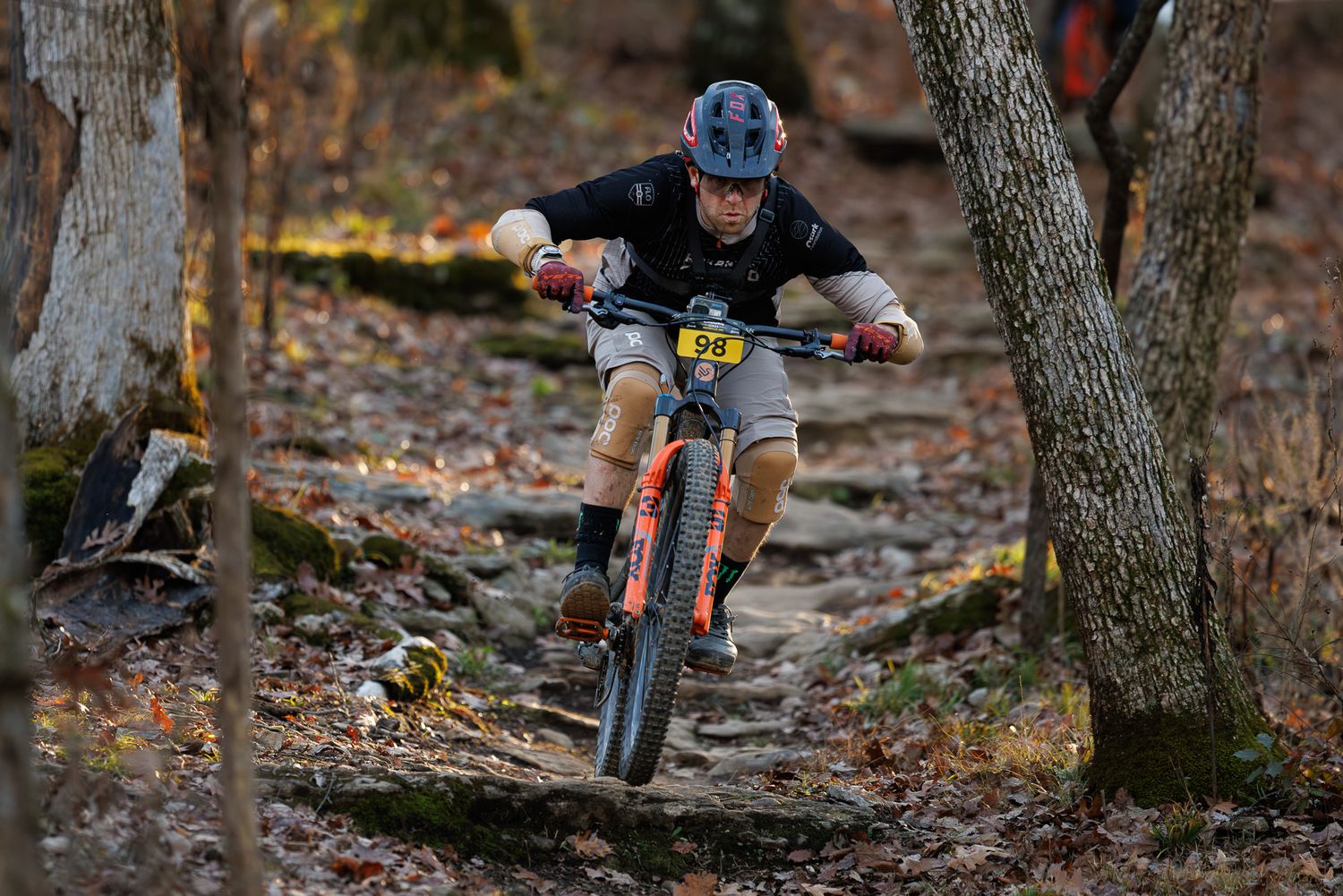 Mountain biker navigates rocky forest trail wearing helmet during an outdoor enduro race.