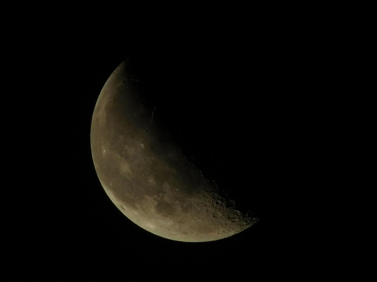 A crescent moon photographed against a dark night sky showing lunar surface details.