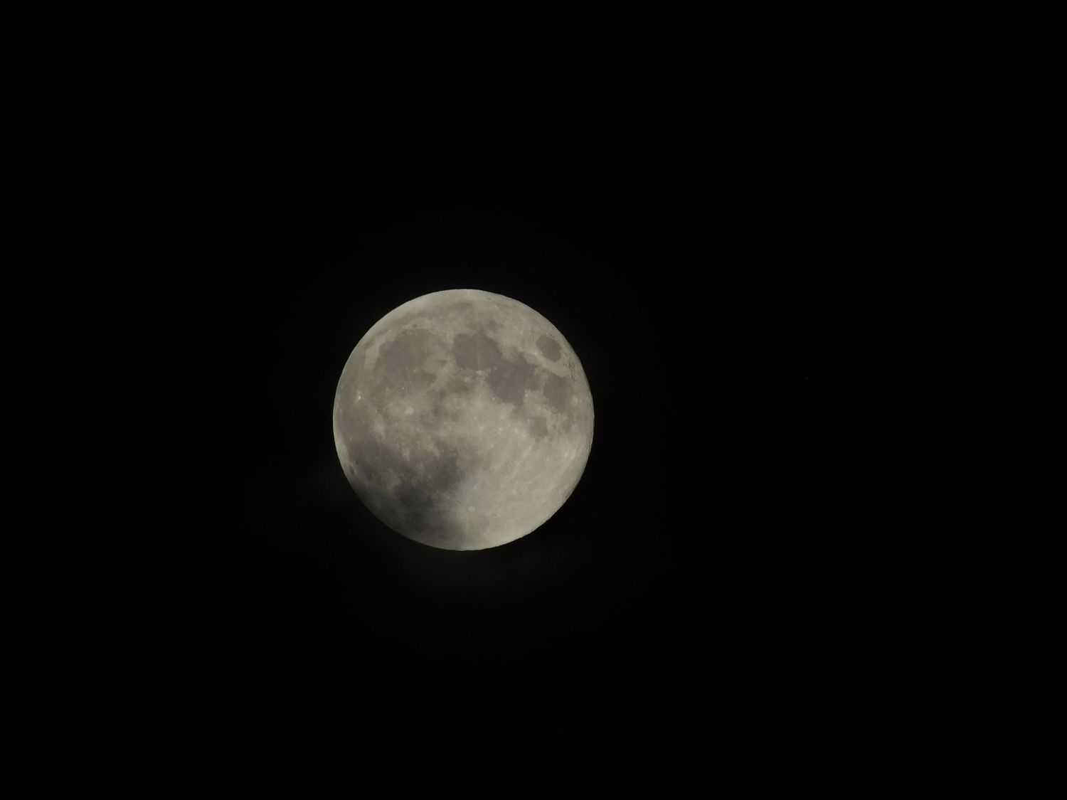 A nearly full moon glowing brightly against a dark night sky with visible lunar craters.