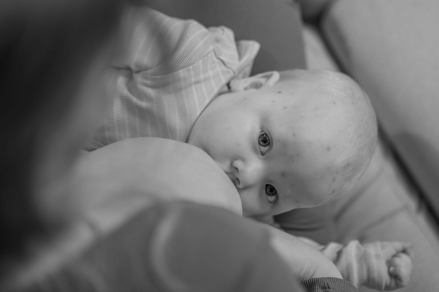 Black and white close-up of a newborn baby breastfeeding peacefully.