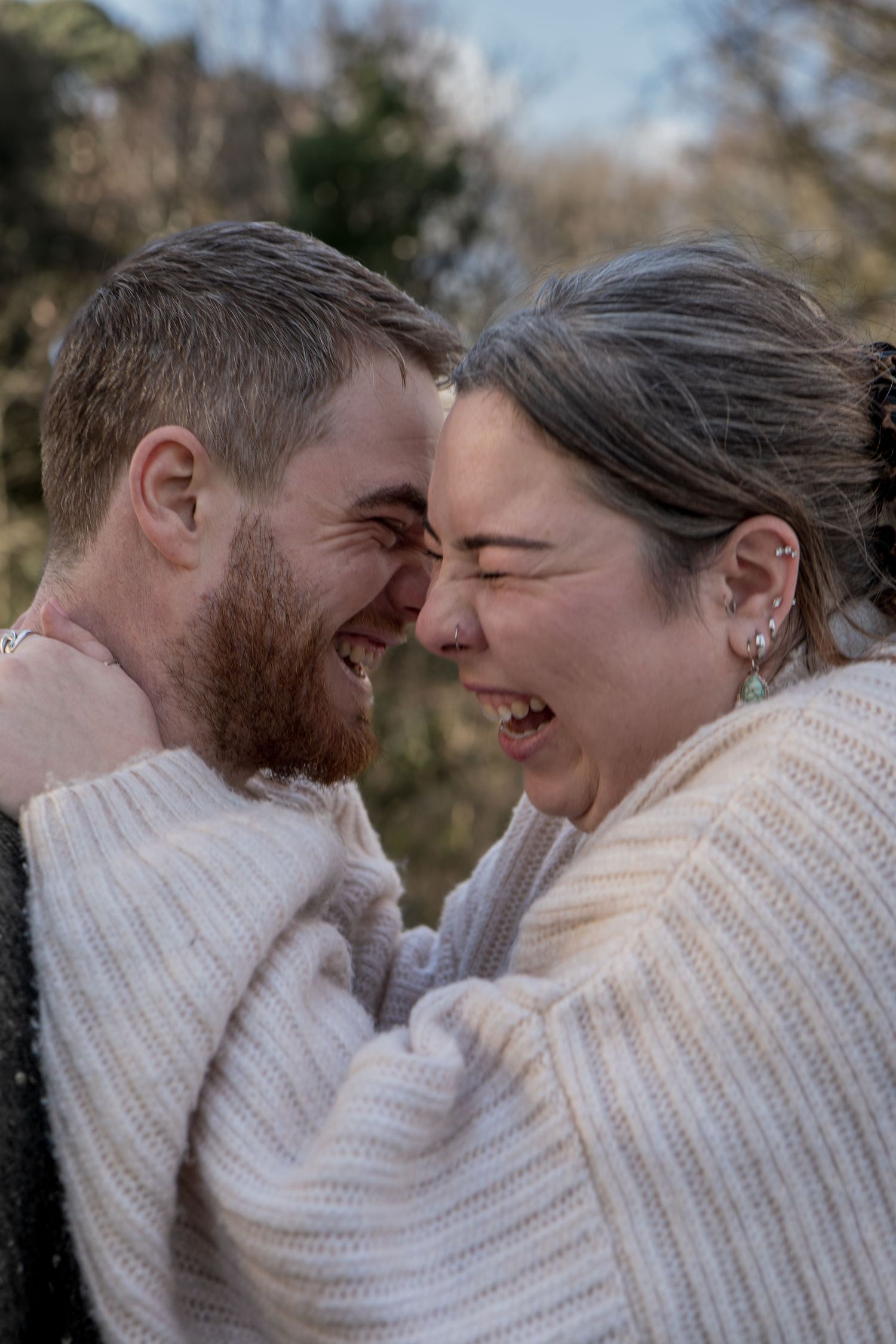 Happy couple laughing together forehead to forehead outdoors in natural light.