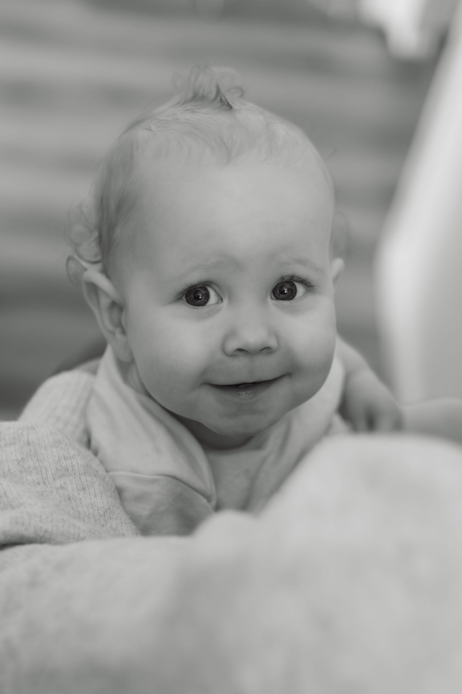 Black and white close-up portrait of a cute smiling baby with bright eyes looking up.