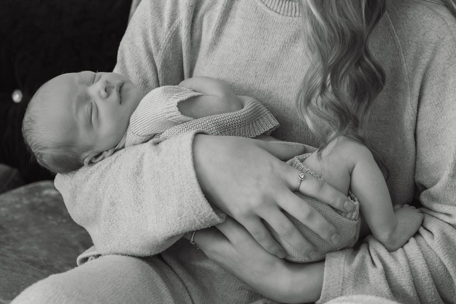 Black and white photo of a mother tenderly holding her sleeping newborn baby.