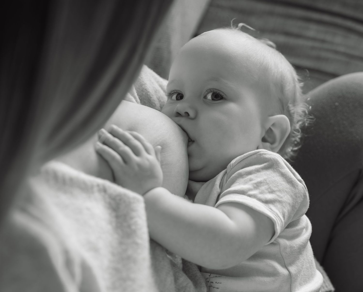 Black and white photo of a mother breastfeeding her infant baby, a tender and natural bonding moment.