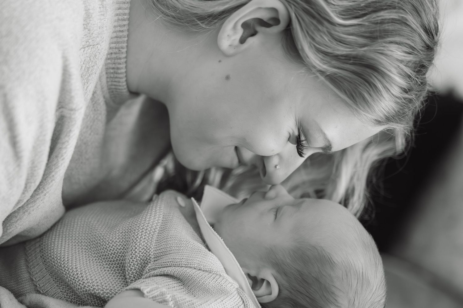 Black and white mother and baby cuddling during newborn photography session at home