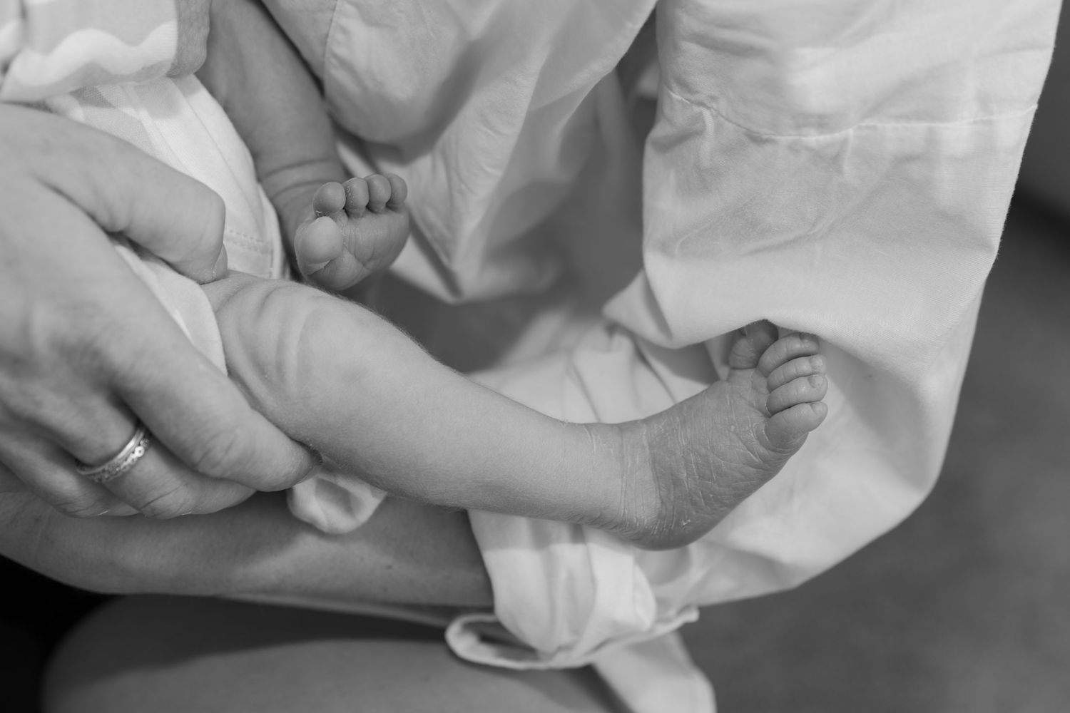 Black and white close up detail of newborn baby feet and little details