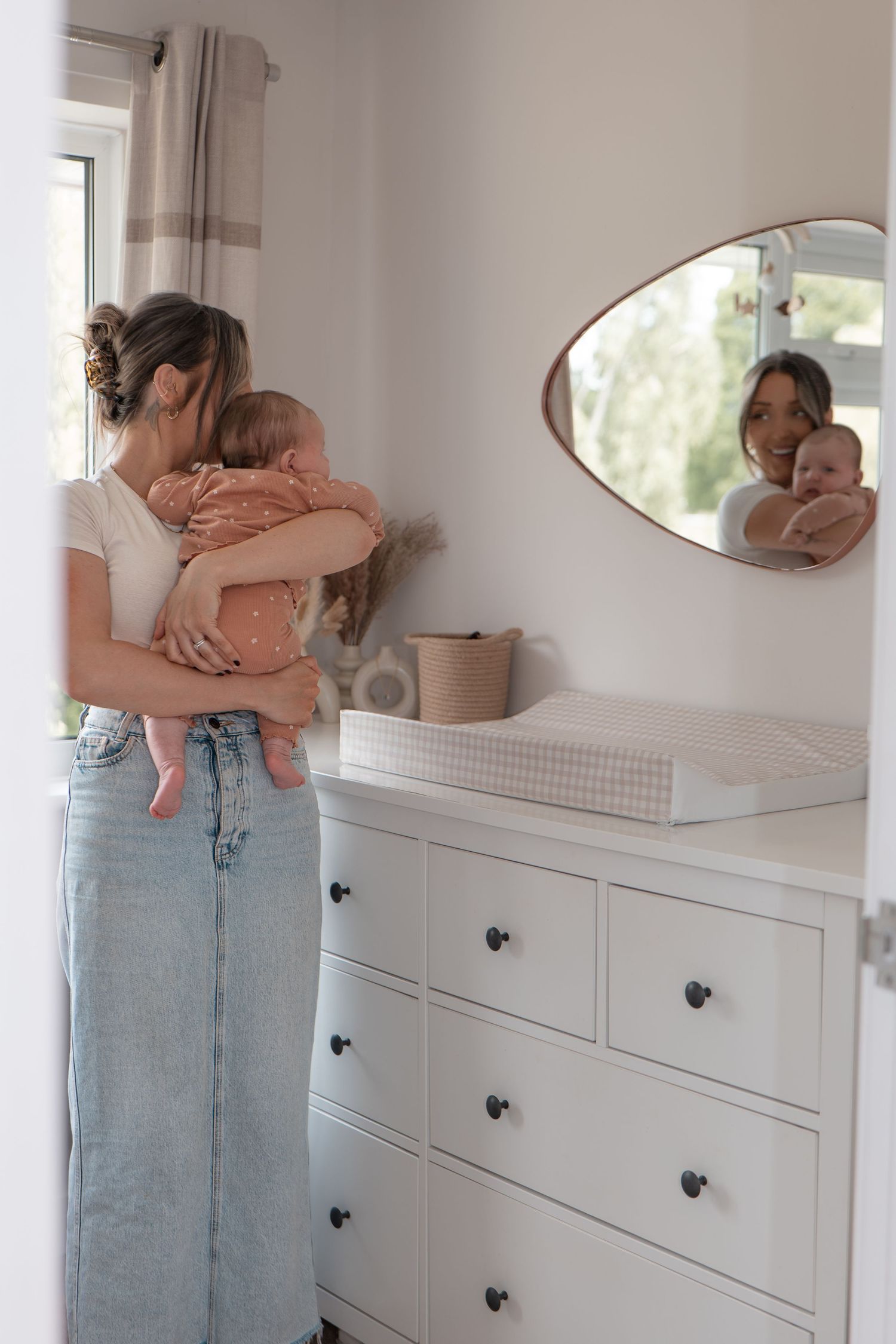 Candid, documentary style photo of mother and baby looking in the mirror at home