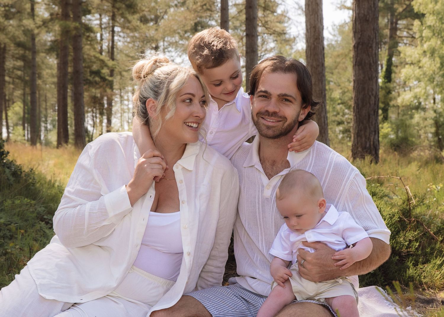 Young family smiling and cuddling candid in the woods
