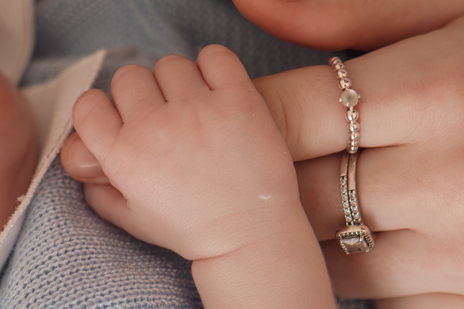 Close up detail of baby hand and mother's rings during newborn photography session at home
