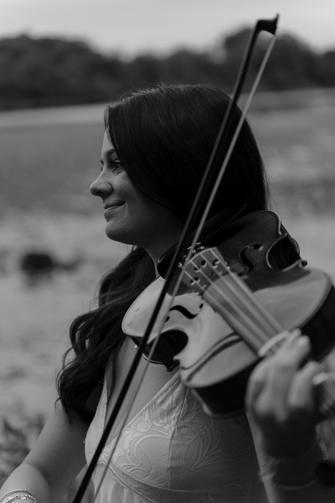 Black and white portrait of woman playing violin outdoors.