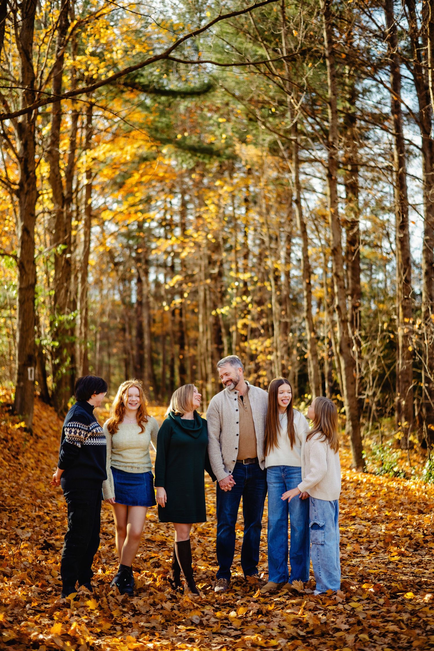 Mom and dad hugging teen kids in the forest during fall. Ottawa Family Photography.