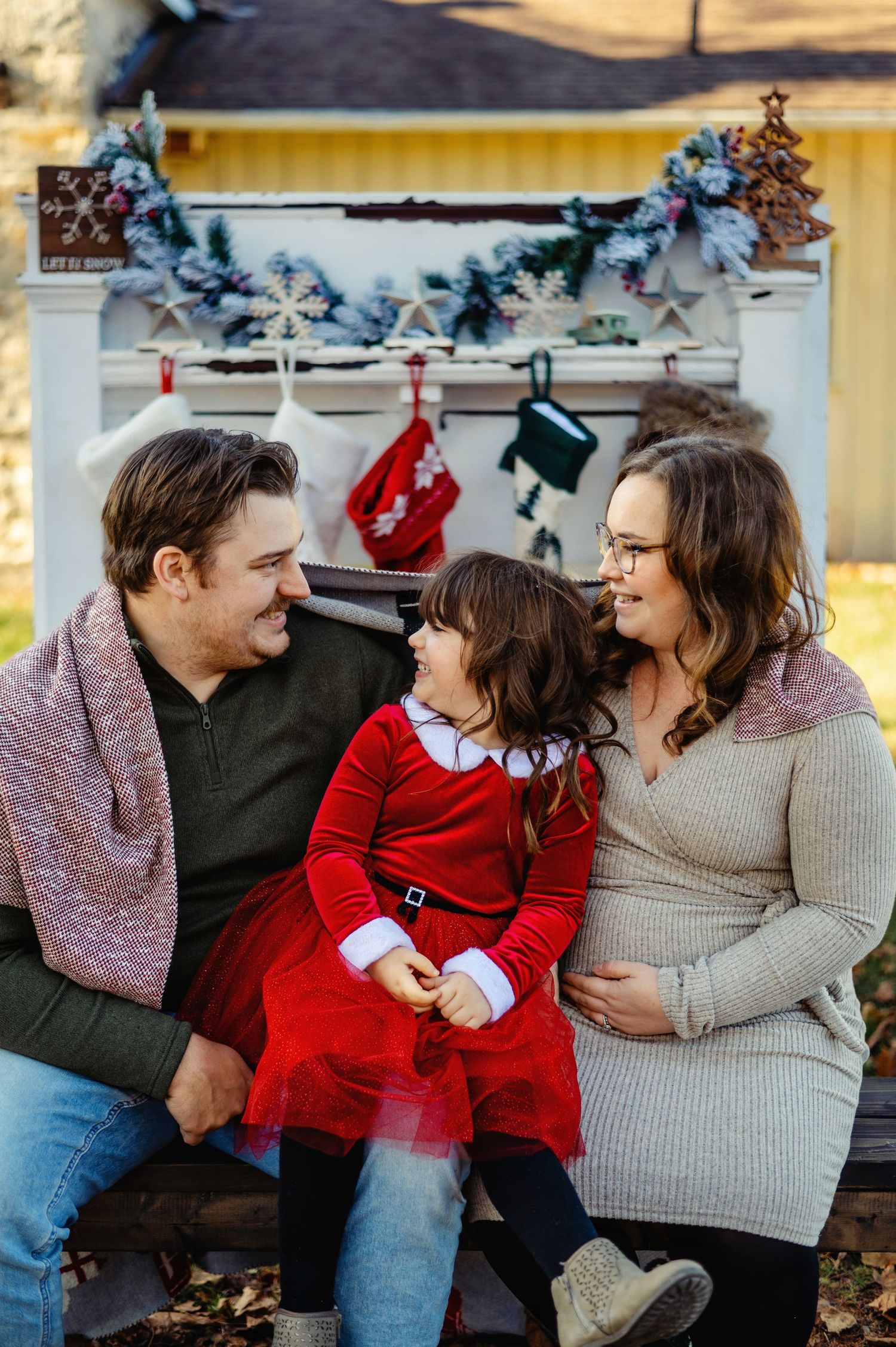 Family sitting by fireplace with stockings hanging and baby coming soon. Ottawa Christmas Mini's Photographer