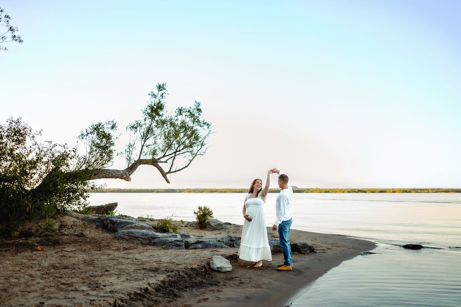 Dancing on the beach while holding baby belly. Ottawa Maternity Photography. Ottawa Family Photographer.