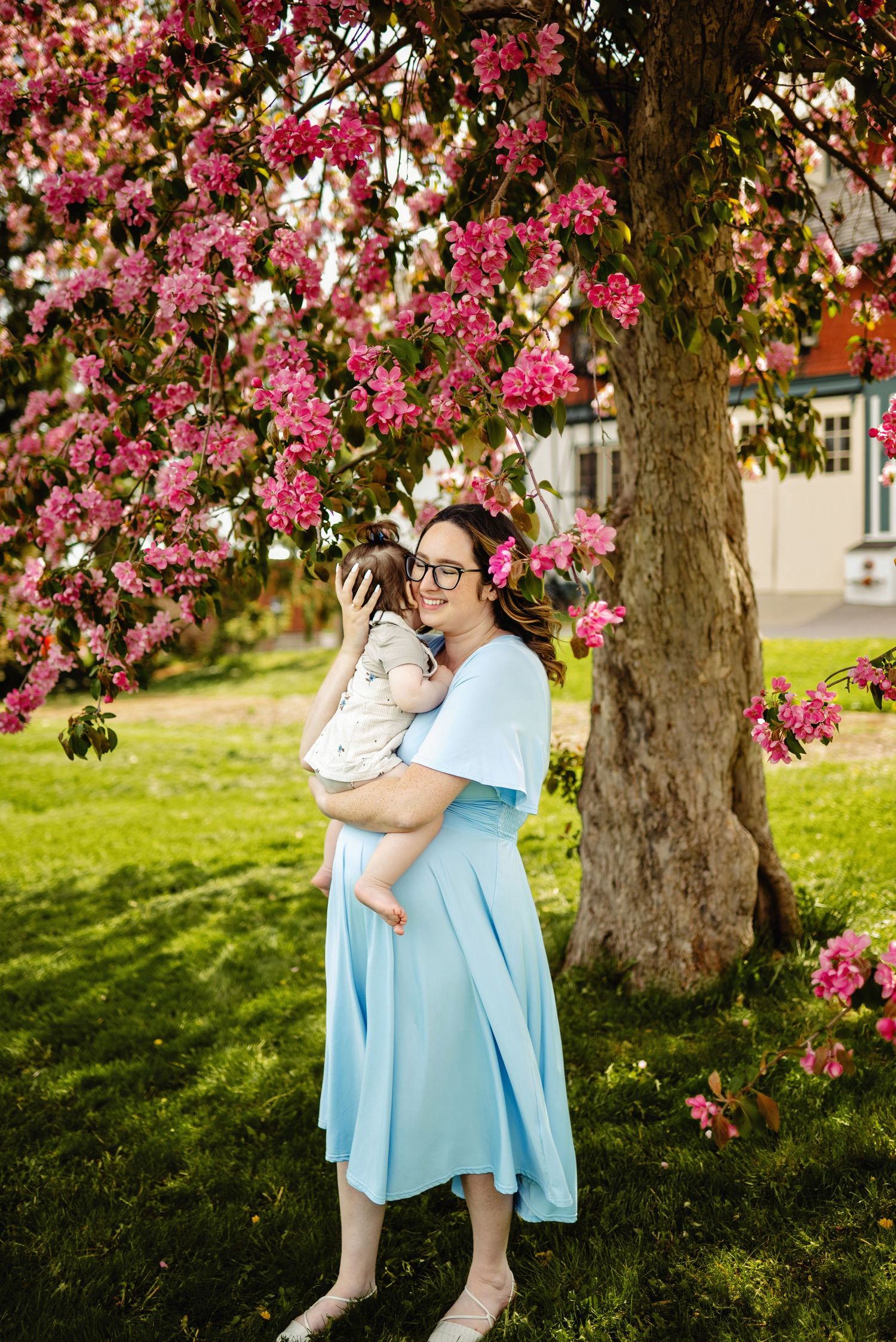 Mom holding daughter to chest in cherry blossoms. Ottawa Family Photographer.