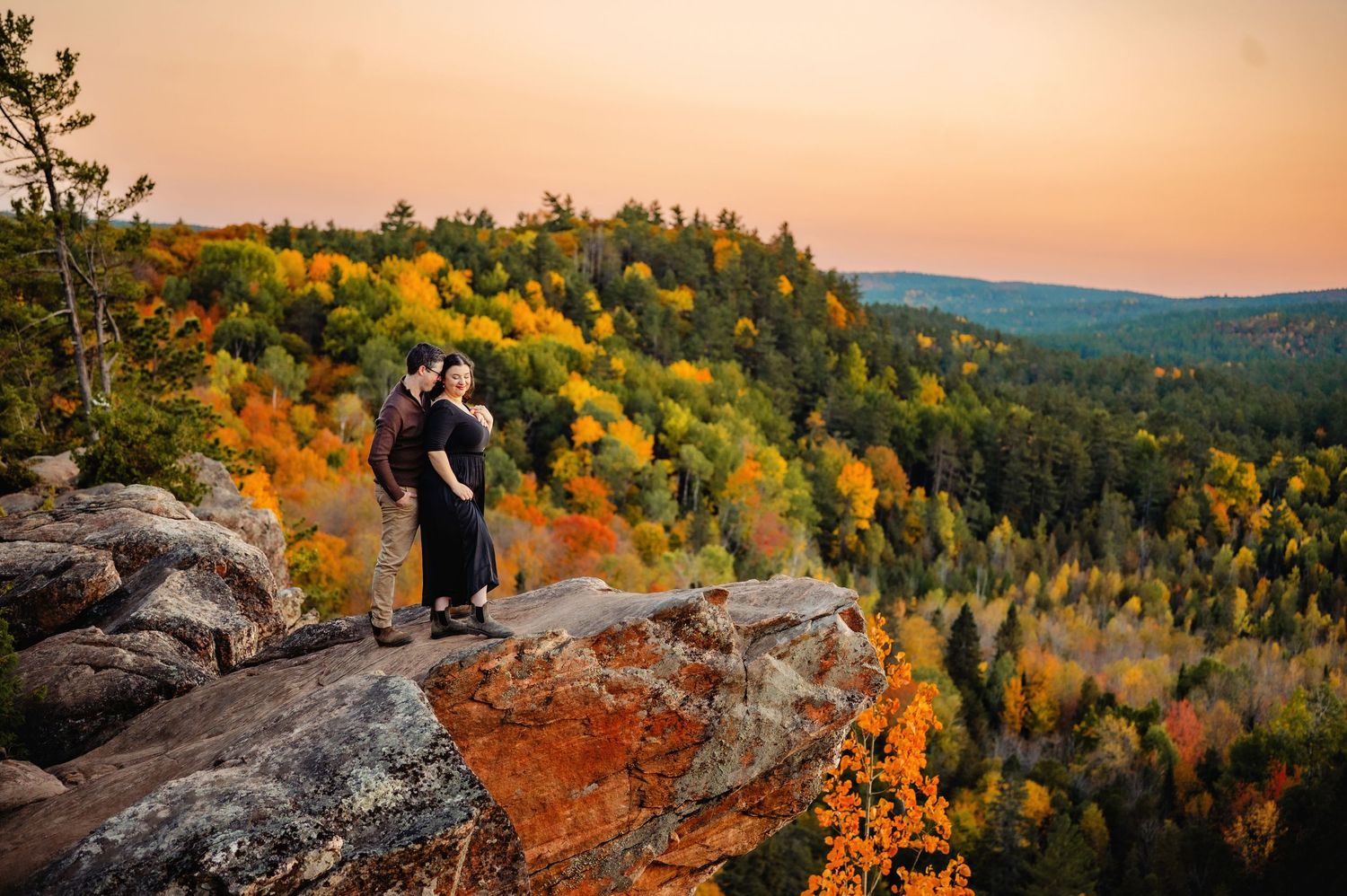 Couple cuddled on rocks edge at Eagles Nest Lookout in Calabogie. Ottawa Wedding Photographer. Ottawa Couples Photographer