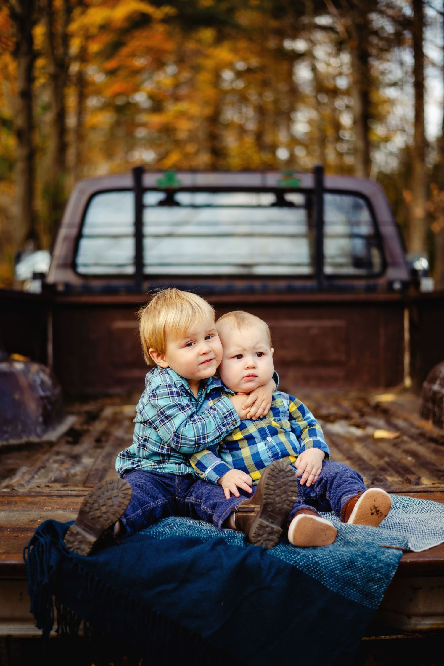 Siblings hugging each other on back of old truck tailgate. Ottawa Family Photographer. Ottawa Fall Minis Photographer