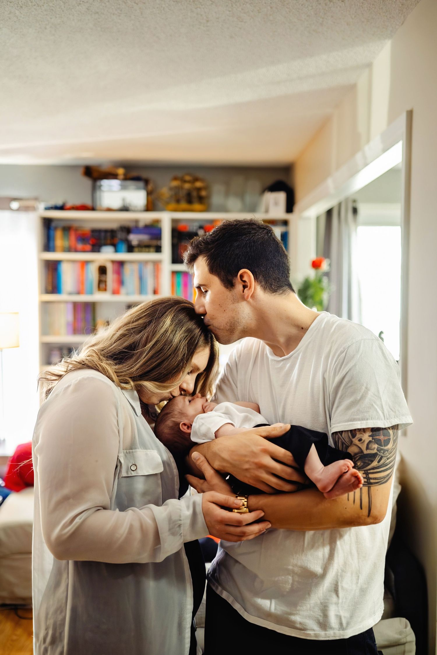 Mom kissing newborn daughter while dad kisses mom. Ottawa Newborn Photography. Ottawa Family Photography