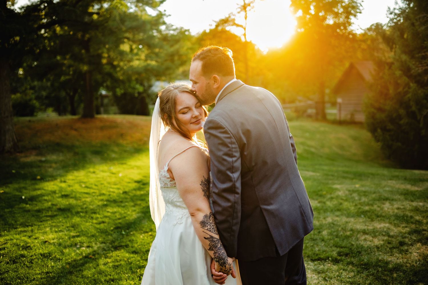 Groom kissing bride on forehead while she looks over her shoulder during sunset. Ottawa Wedding Photography. Ottawa Wedding Videography.