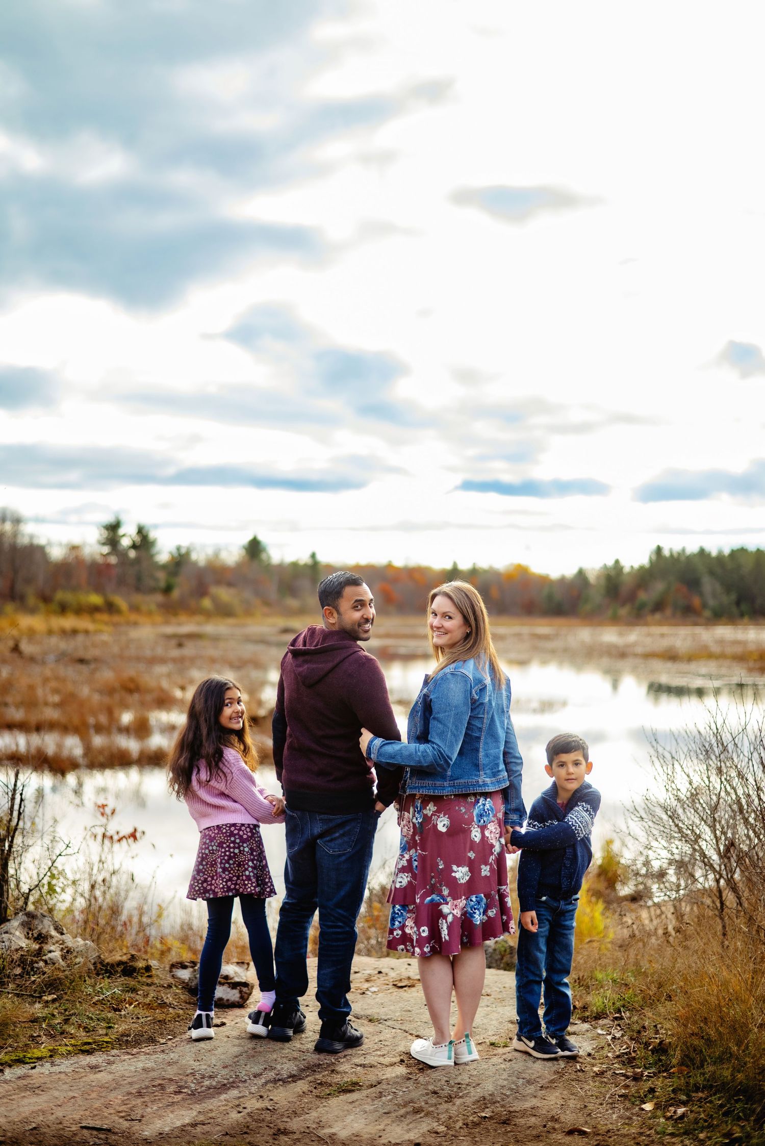 Family looking back over their shoulders at camera by the water. Ottawa Family Photography.