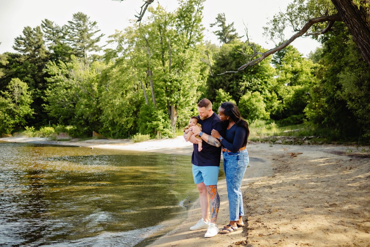 Mom and dad looking at son while on beach in summer. Ottawa Family Photographer.