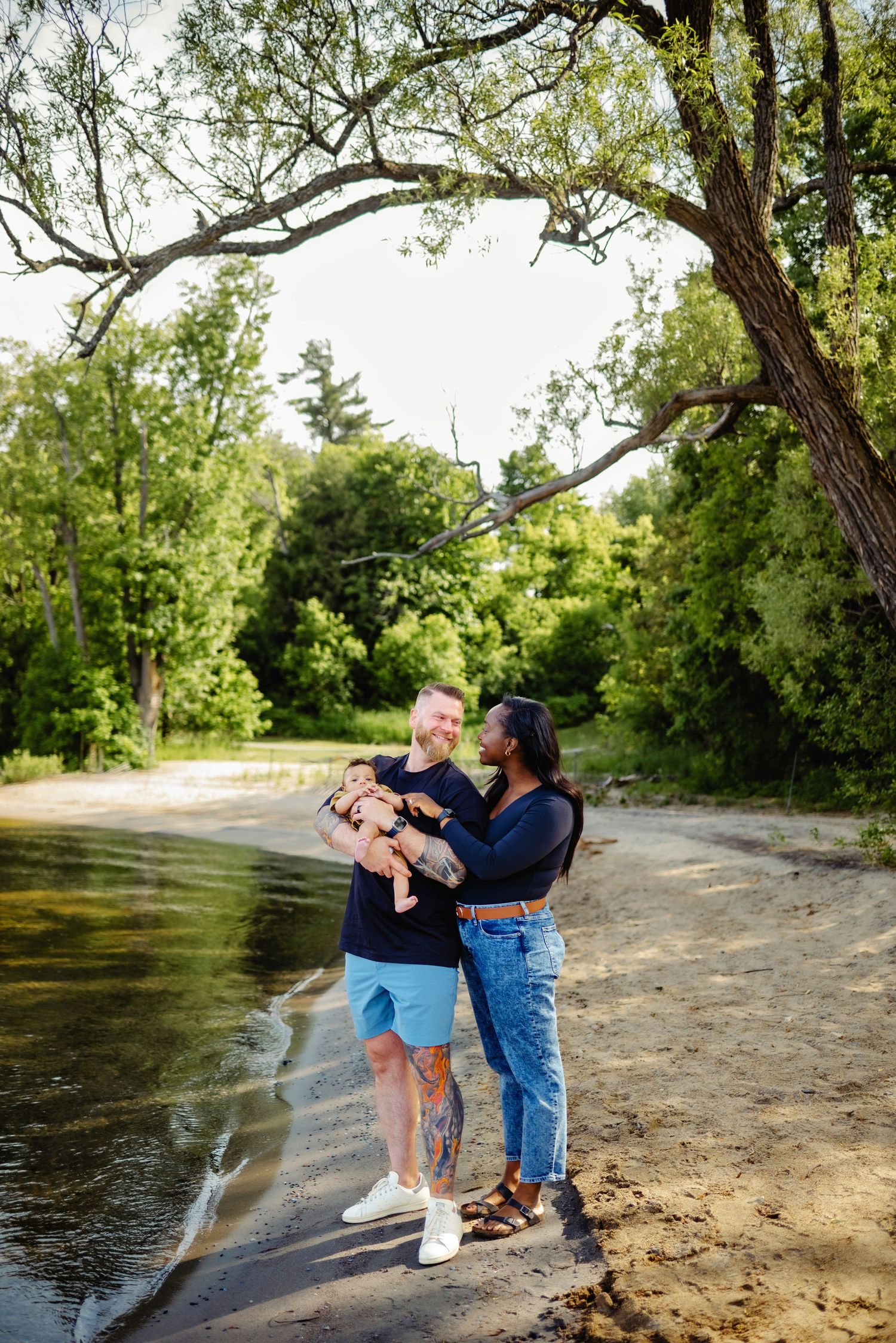 Dad and mom looking at each other while holding son on the beach. Ottawa Family Photography