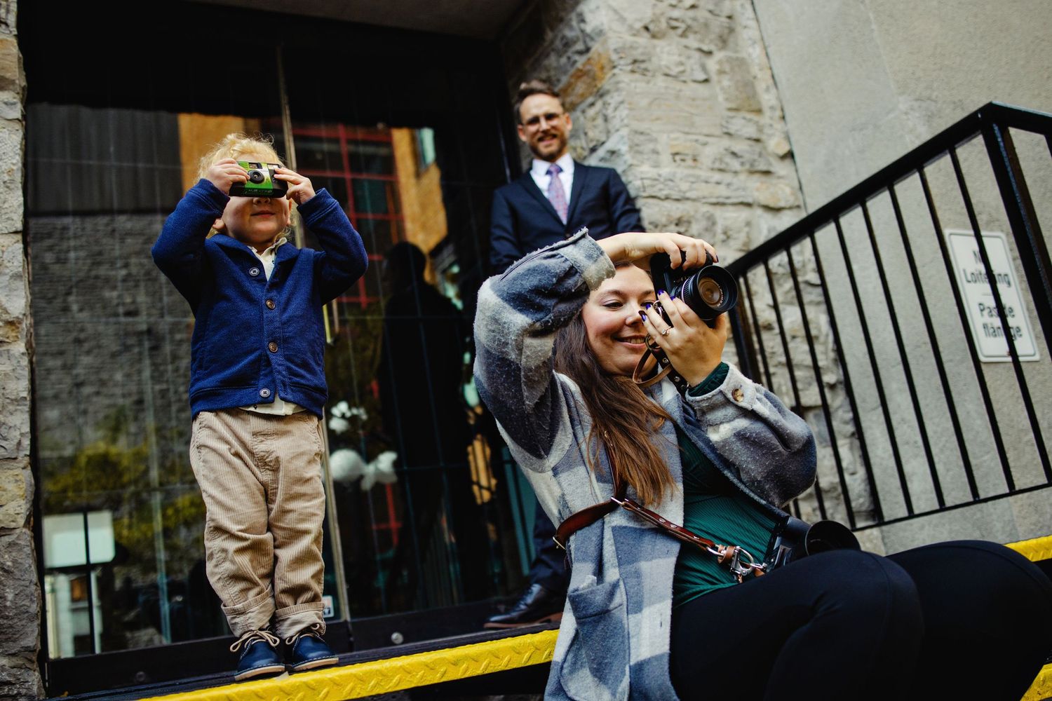 Shauna taking photos while a child wedding guest pretends to take photos beside me. Ottawa Wedding Photographer and Videographer