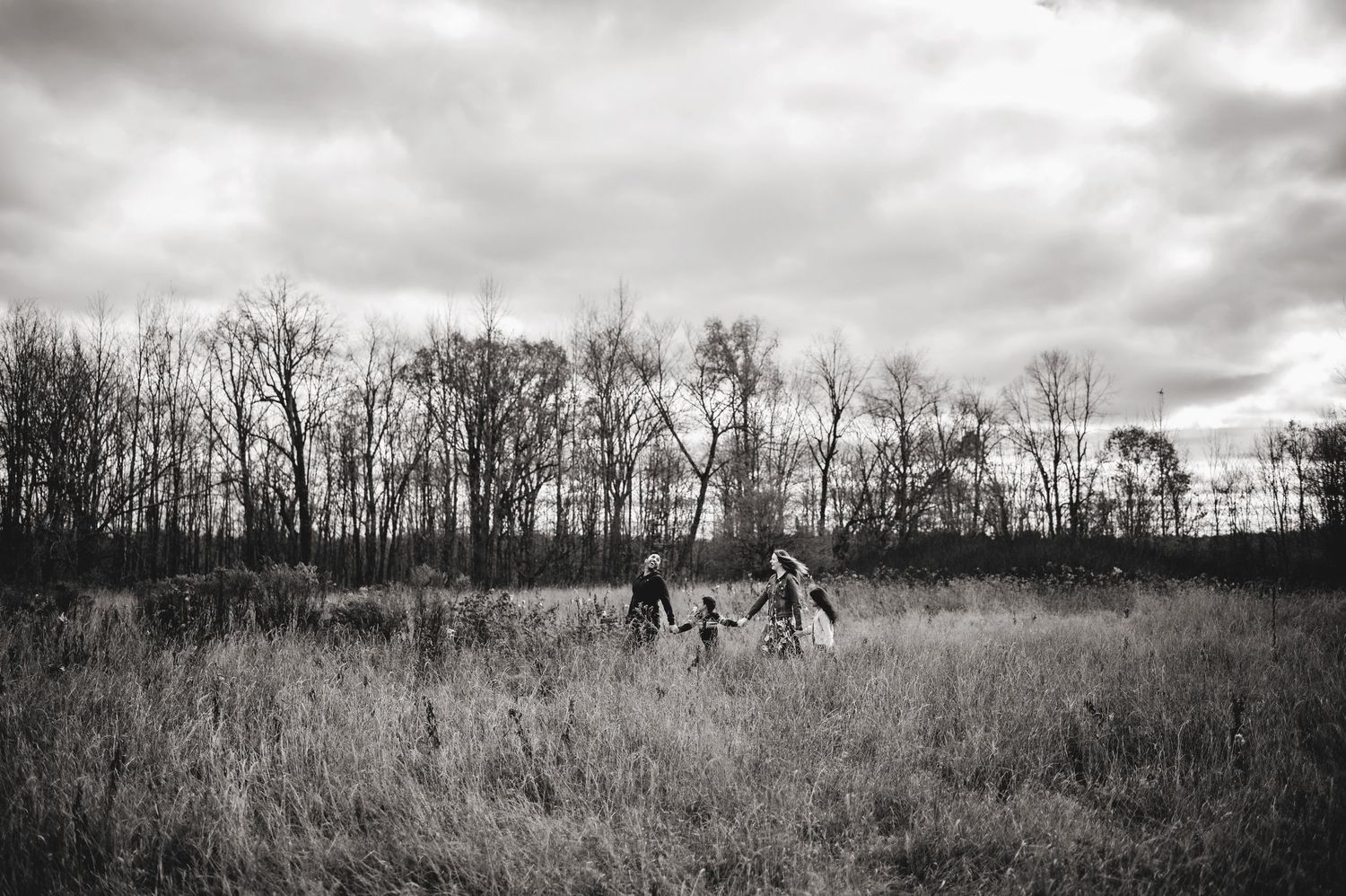 Family walking in the tall grass holding hands. Ottawa Family Photography