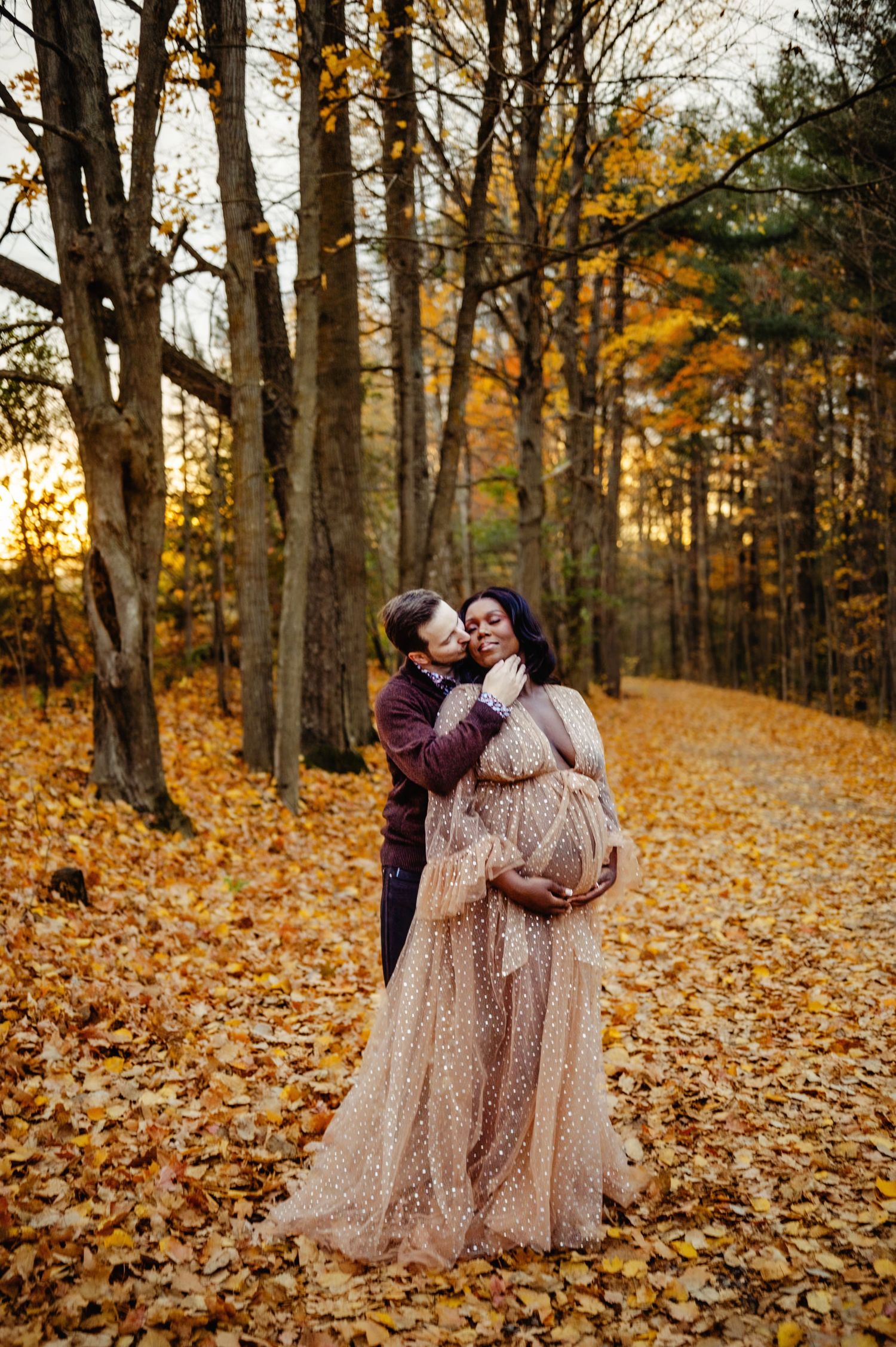 Husband kissing wife on cheek while she holds baby belly. Ottawa Maternity Photographer. Ottawa Family Photographer.